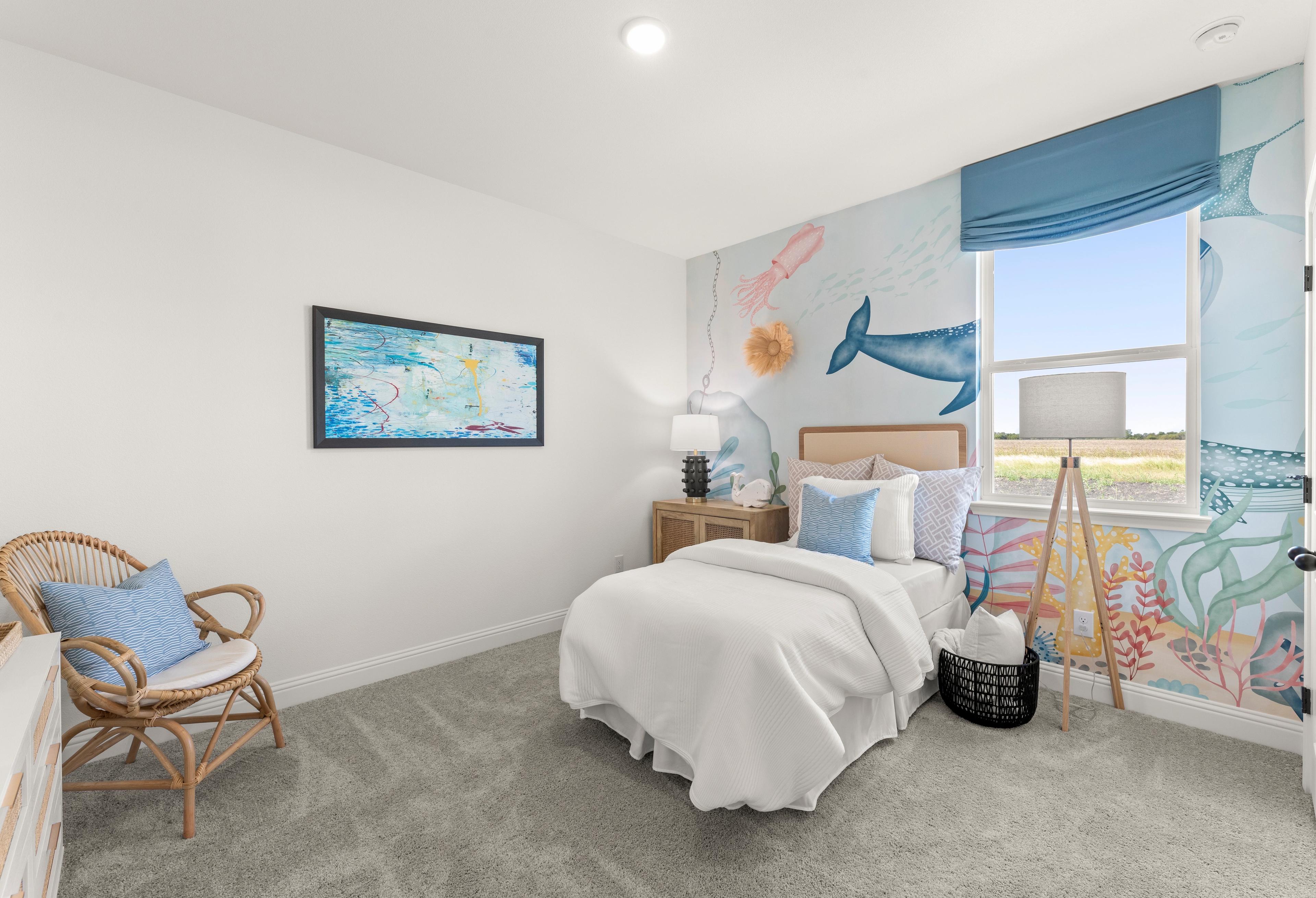 Ocean-themed kids bedroom in The Laurel G with underwater mural, white bed, wicker chair, blue curtains