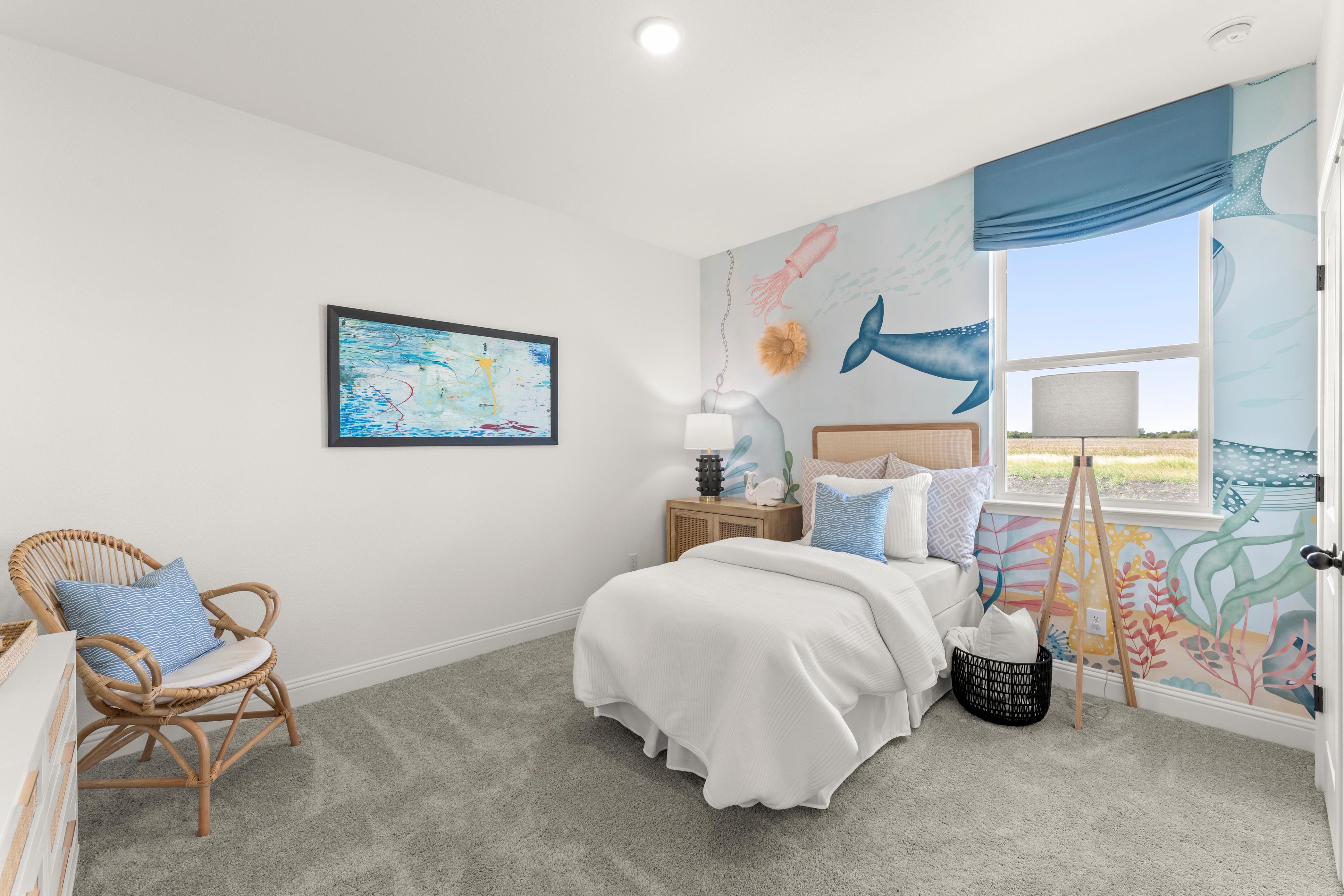Cozy ocean-themed child's bedroom at Meadow Ridge Estates in Josephine Texas with sea mural, white bed and wicker chair