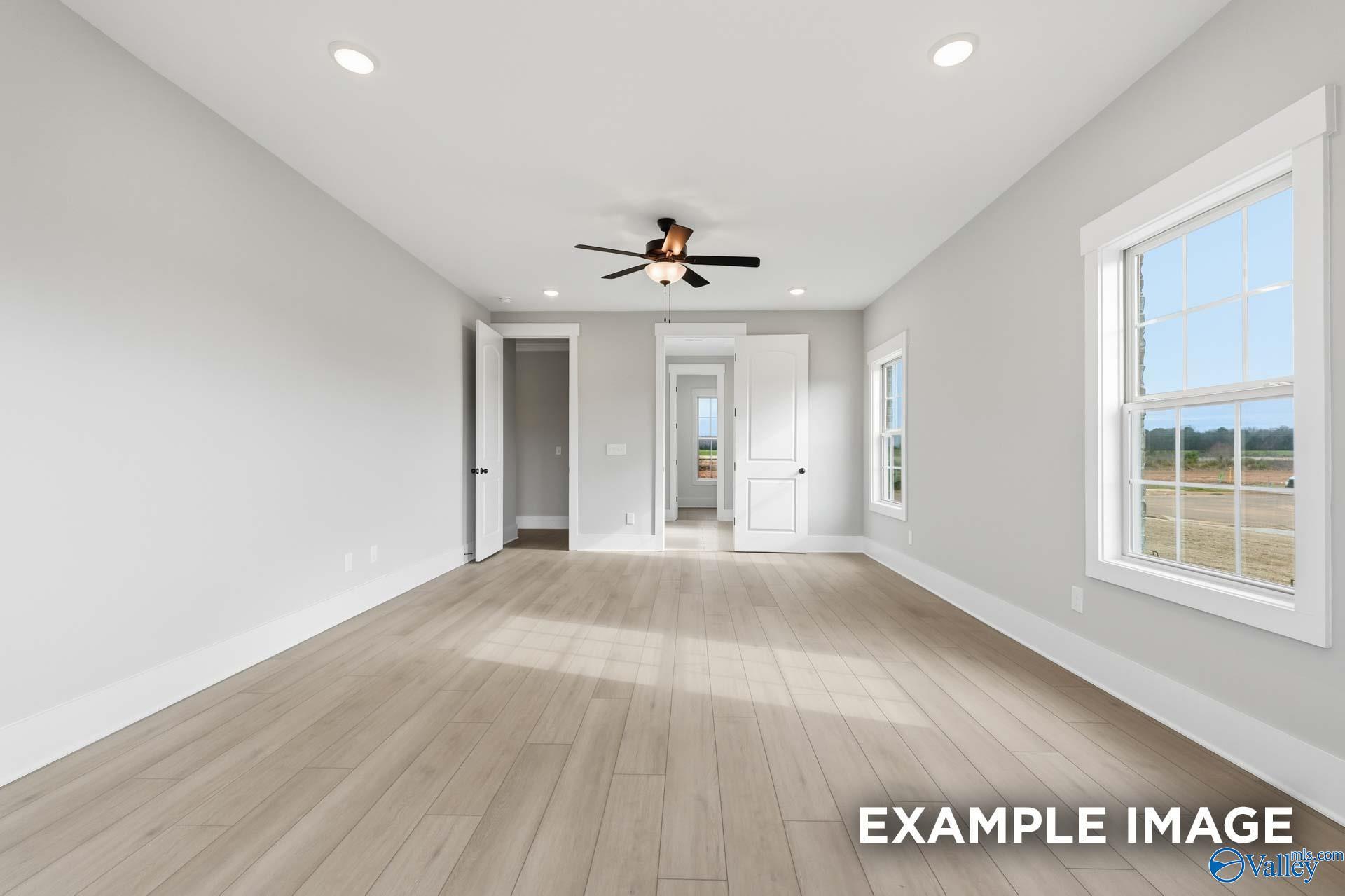 Spacious bedroom with ceiling fan, large windows, and hardwood floors in Davidson Homes The Emory, Hollon Meadow, Decatur, Alabama