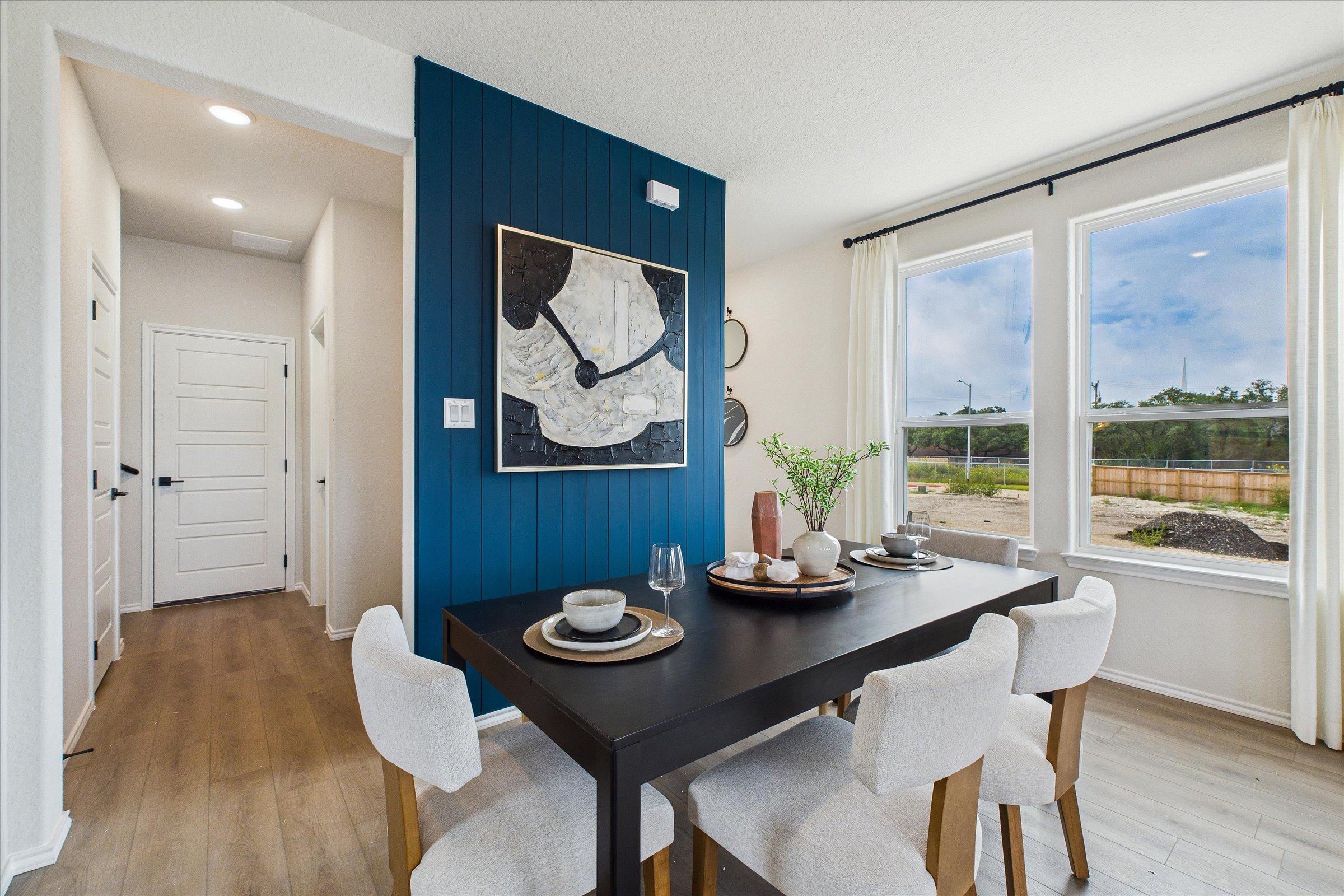 Spacious dining room in Meadows at Oak Creek San Antonio TX with navy blue accent wall, abstract art, black table, white chairs, hardwood floors