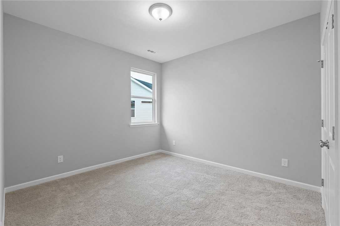 Bright secondary bedroom with gray walls, beige carpet, window, and double doors in Davidson Homes The Luna B, Opelika, Alabama