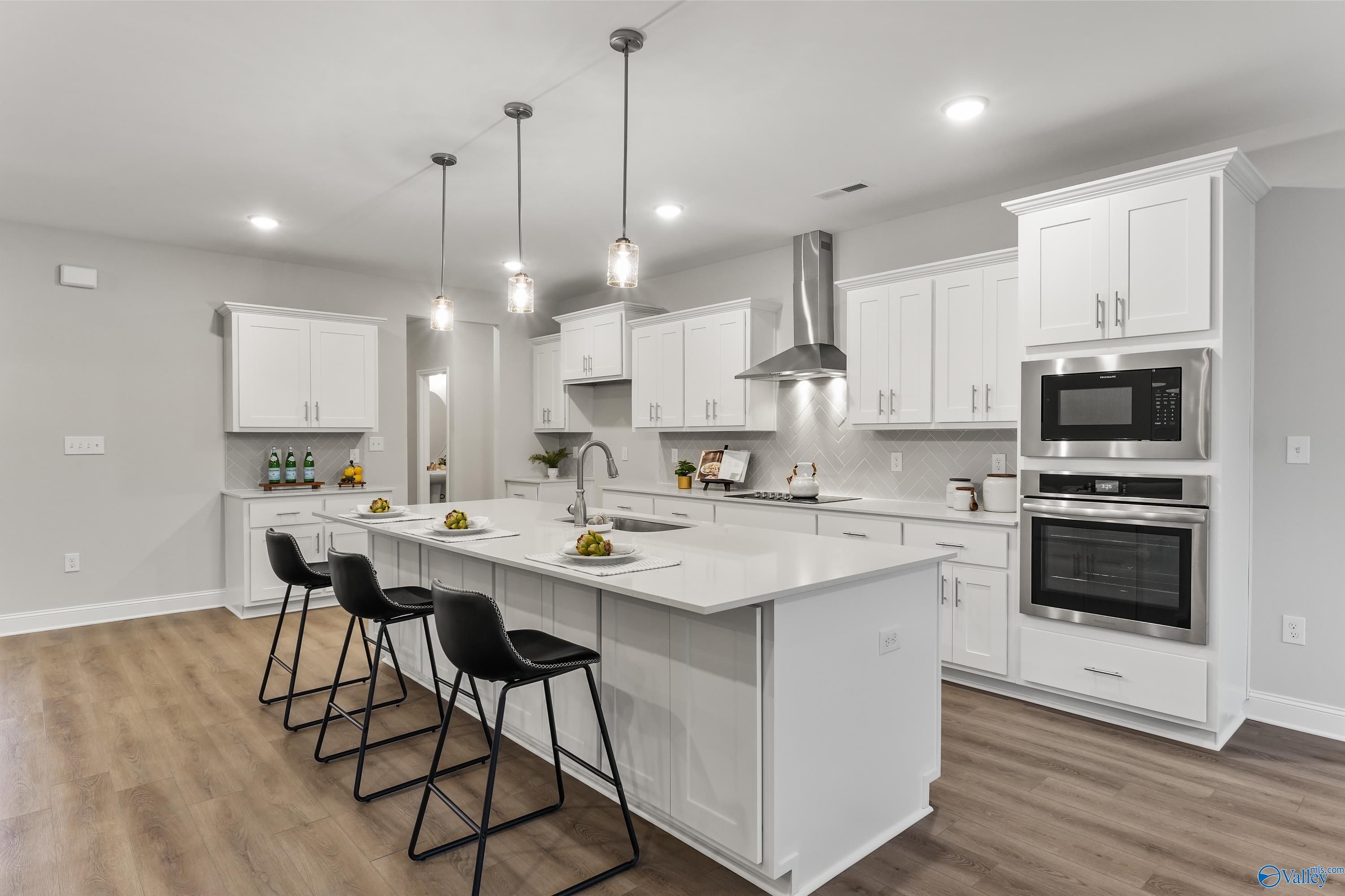 Modern white kitchen with quartz island, stainless steel appliances, and pendant lights in Davidson Homes The Finleigh, Toney, Alabama