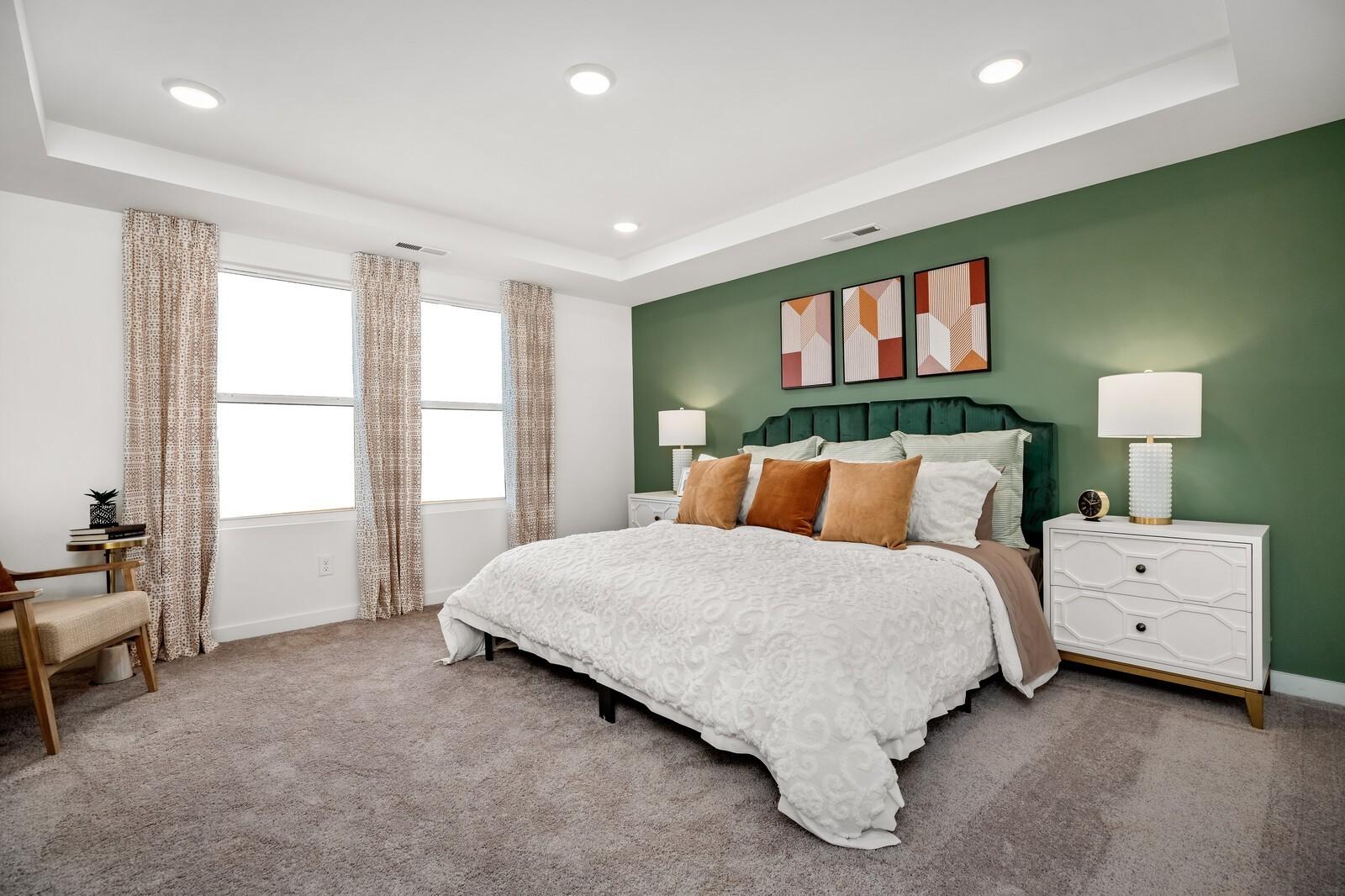 Elegant master bedroom with green accent wall, king bed, orange pillows, and abstract art in Davidson Homes The Gordon C, White House TN