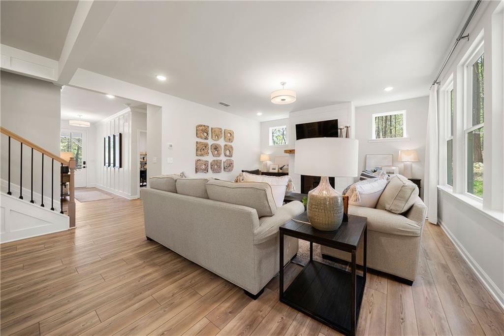 Cozy living room with beige sofas, wooden floors, large windows, and wall art in Davidson Homes The Willow B, Riverwood, Dallas, Georgia