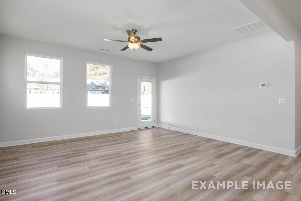 Bright living room with ceiling fan, large windows, sliding glass door, hardwood floors in Davidson Homes Adalynn A, Lillington, NC