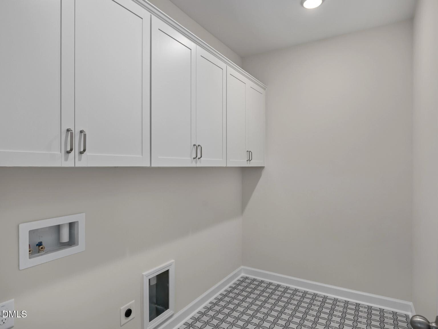 Modern laundry room with white shaker cabinets, washer-dryer nook, pet door, and gray checkered tile in The Beech B by Davidson Homes, Wake Forest, NC