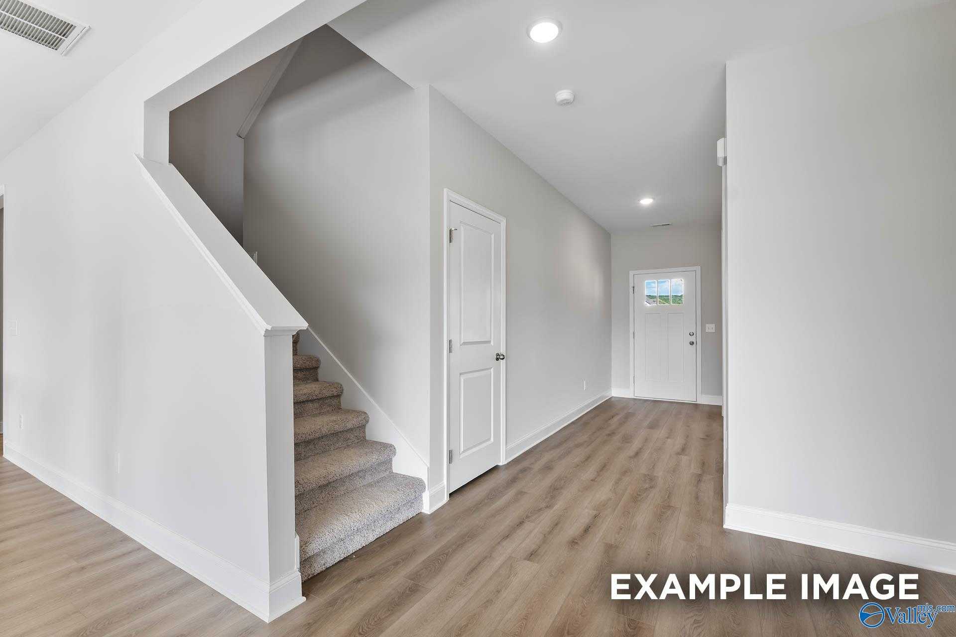Bright hallway with carpeted staircase and hardwood floors in Davidson Homes The Chelsea A, Athens, Alabama