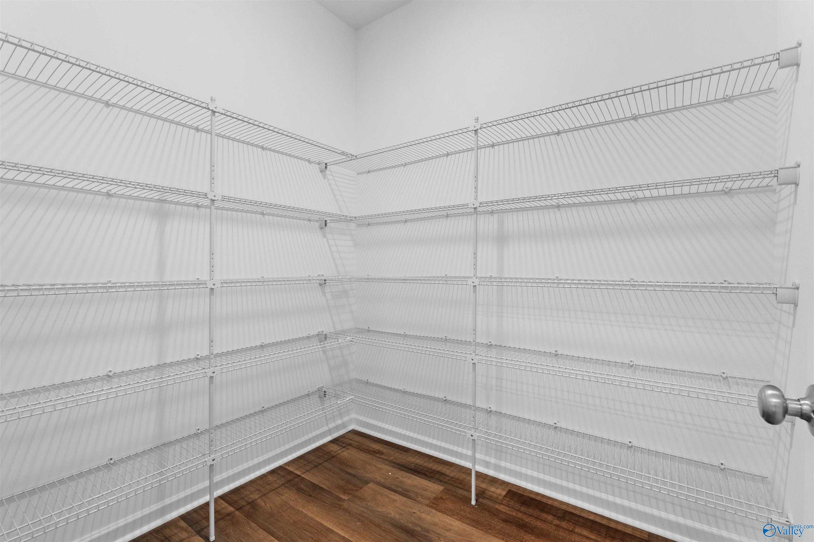 Spacious walk-in closet with white wire shelving and hardwood floors in Davidson Homes The Luna, Hazel Green, Alabama