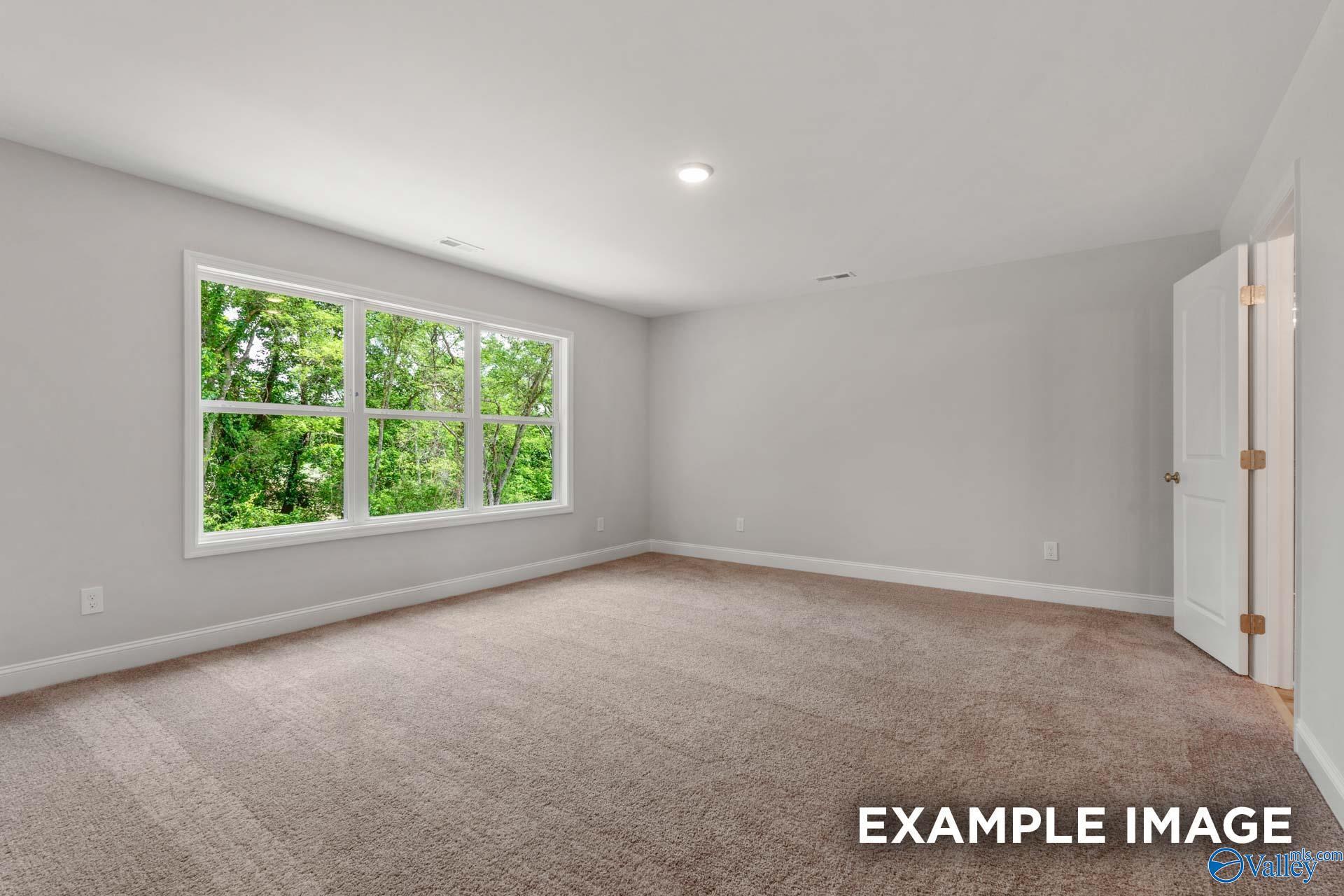 Bright empty bedroom with large triple windows and tree views in Davidson Homes Shelby C, Meridianville, AL