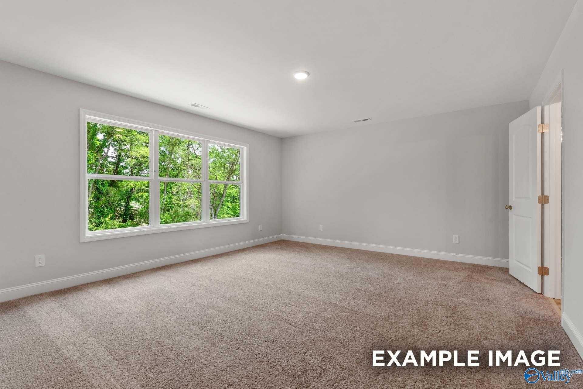 Bright empty bedroom with large triple windows and tree views in Davidson Homes Shelby C, Meridianville, AL