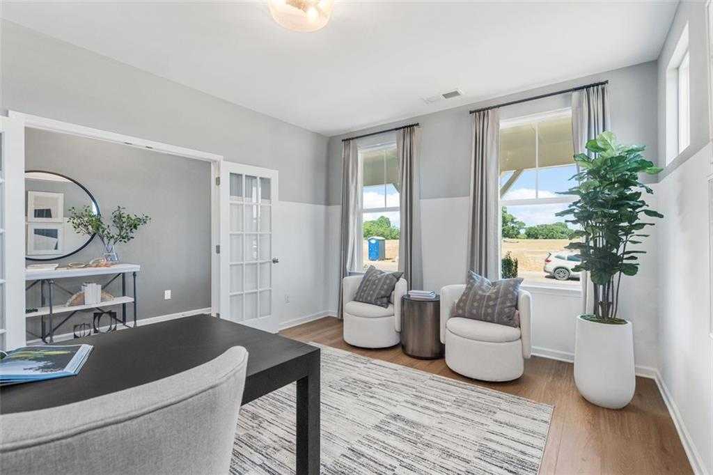 Cozy home office with wooden desk, armchairs, potted plants, and large windows in 5-bedroom Davidson Homes The Hickory B, Hoschton, GA