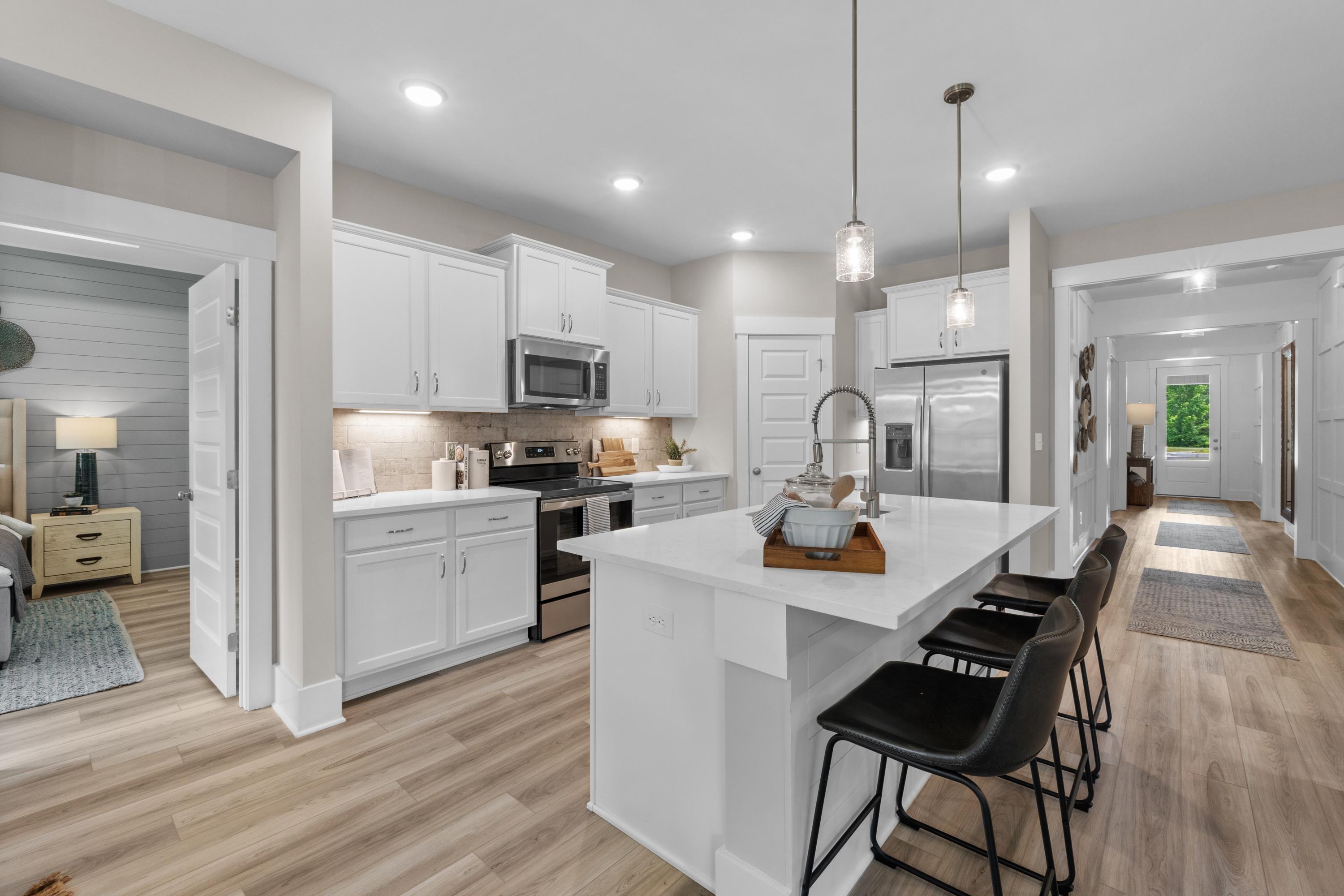 Spacious white kitchen with island bar, stainless appliances, and pendant lights at The Highlands in Arab, Alabama