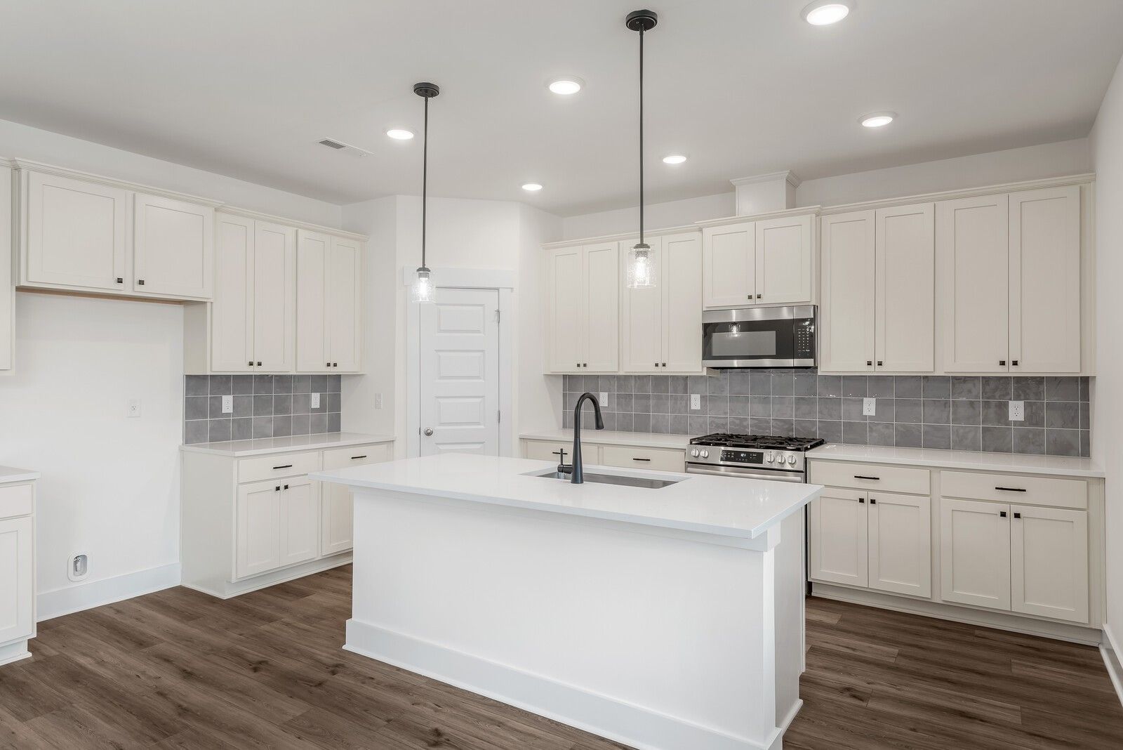 Modern white kitchen with large island, stainless steel appliances, subway tile backsplash in The Logan C, Davidson Homes, Gallatin TN