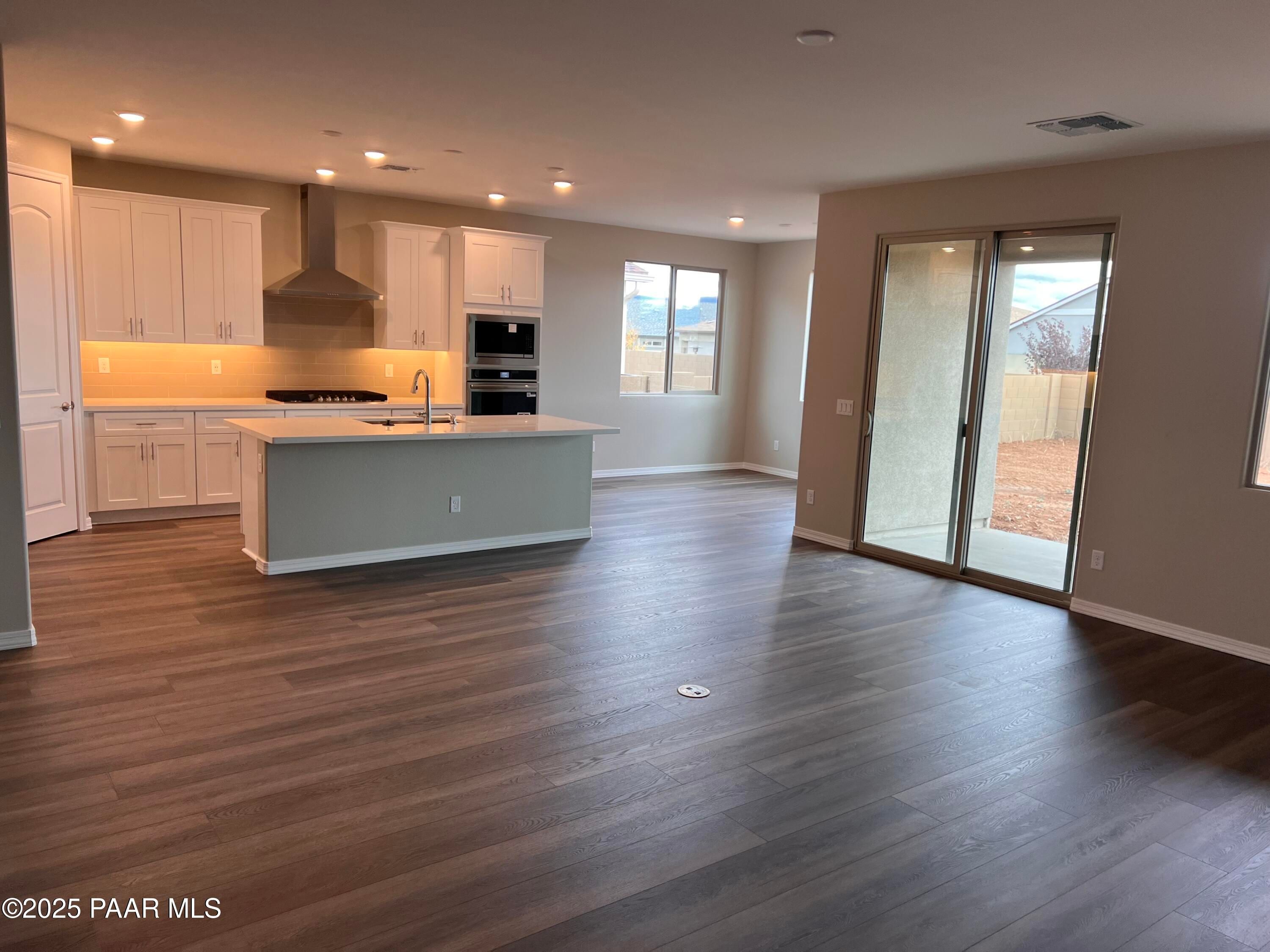 Modern open kitchen with white shaker cabinets, stainless appliances, and island in The Harmony A 3-bedroom home, Prescott Valley, AZ
