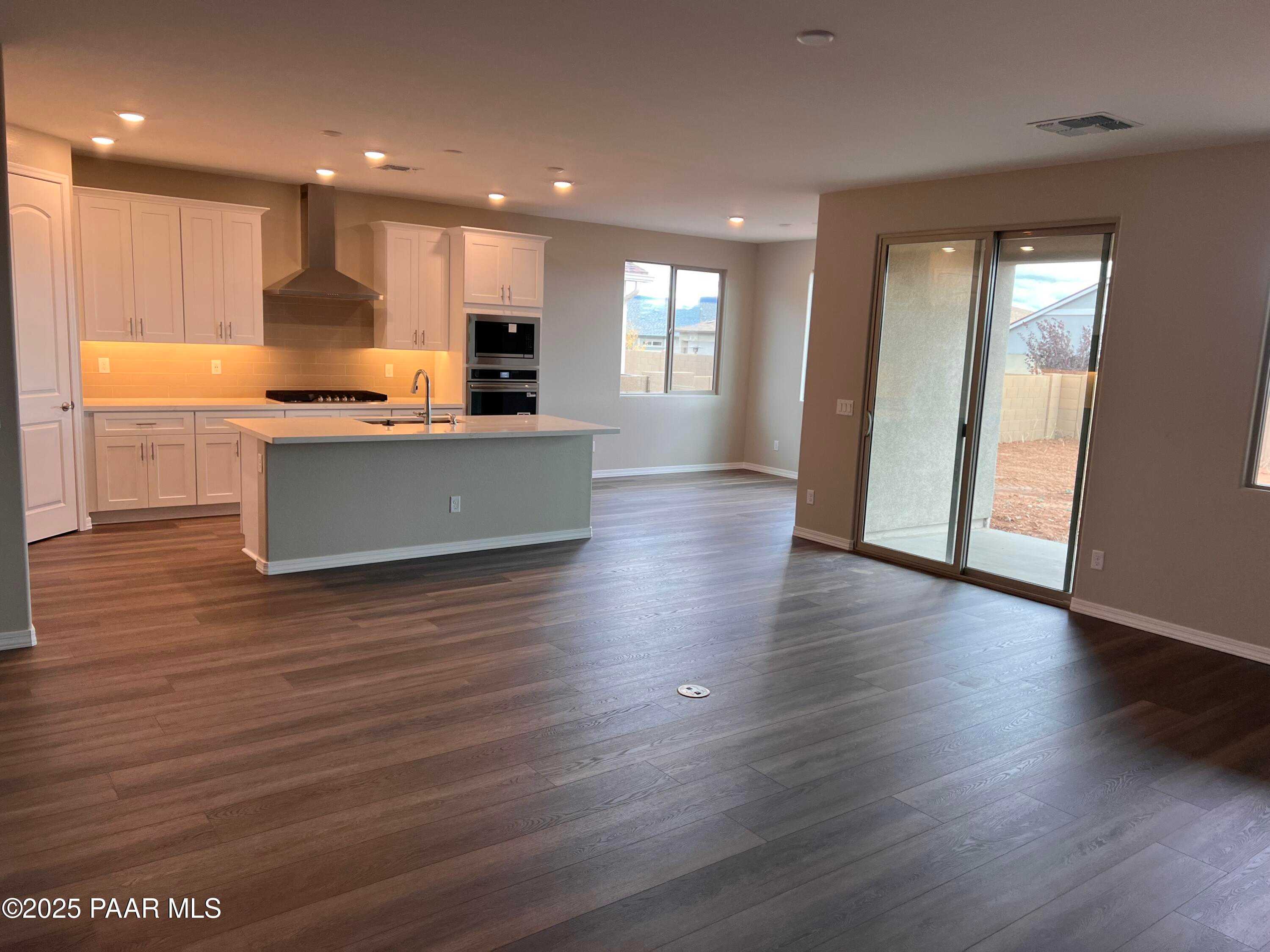 Modern open kitchen with white shaker cabinets, stainless appliances, and island in The Harmony A 3-bedroom home, Prescott Valley, AZ