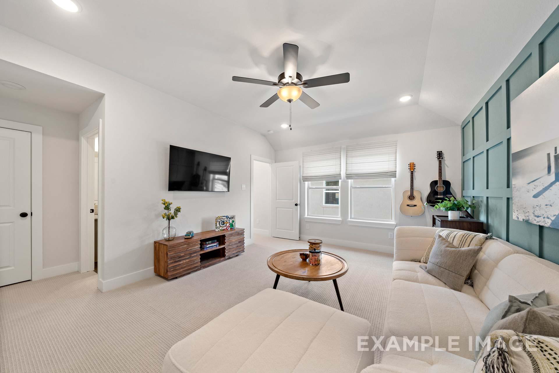 Cozy living room in The Edward A by Davidson Homes, featuring L-shaped beige sofa, mounted TV, wooden console, guitar on teal accent wall