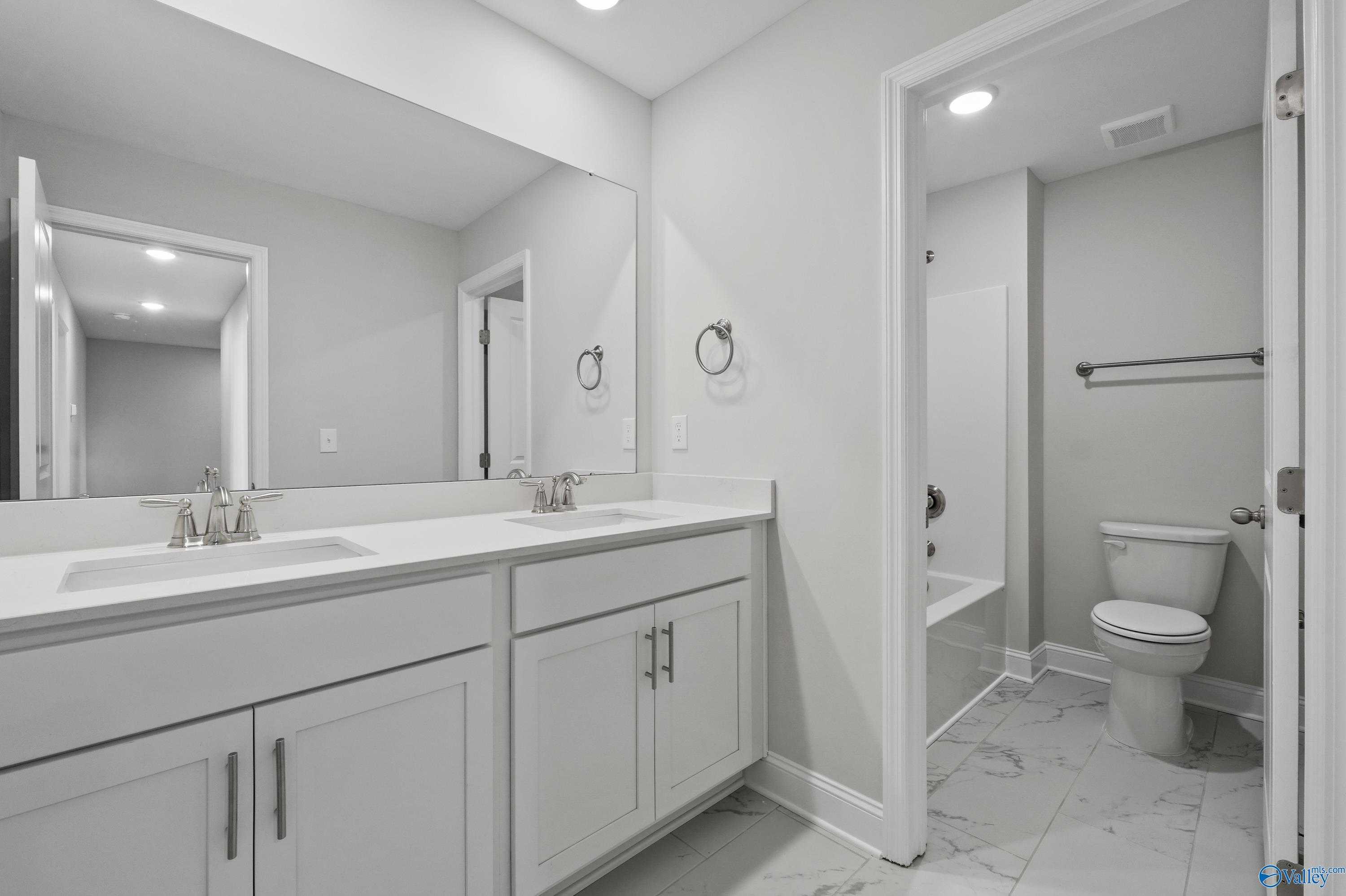 Modern master bathroom with double vanity sinks, soaking tub, and tile flooring in Davidson Homes The Camden, Huntsville, Alabama