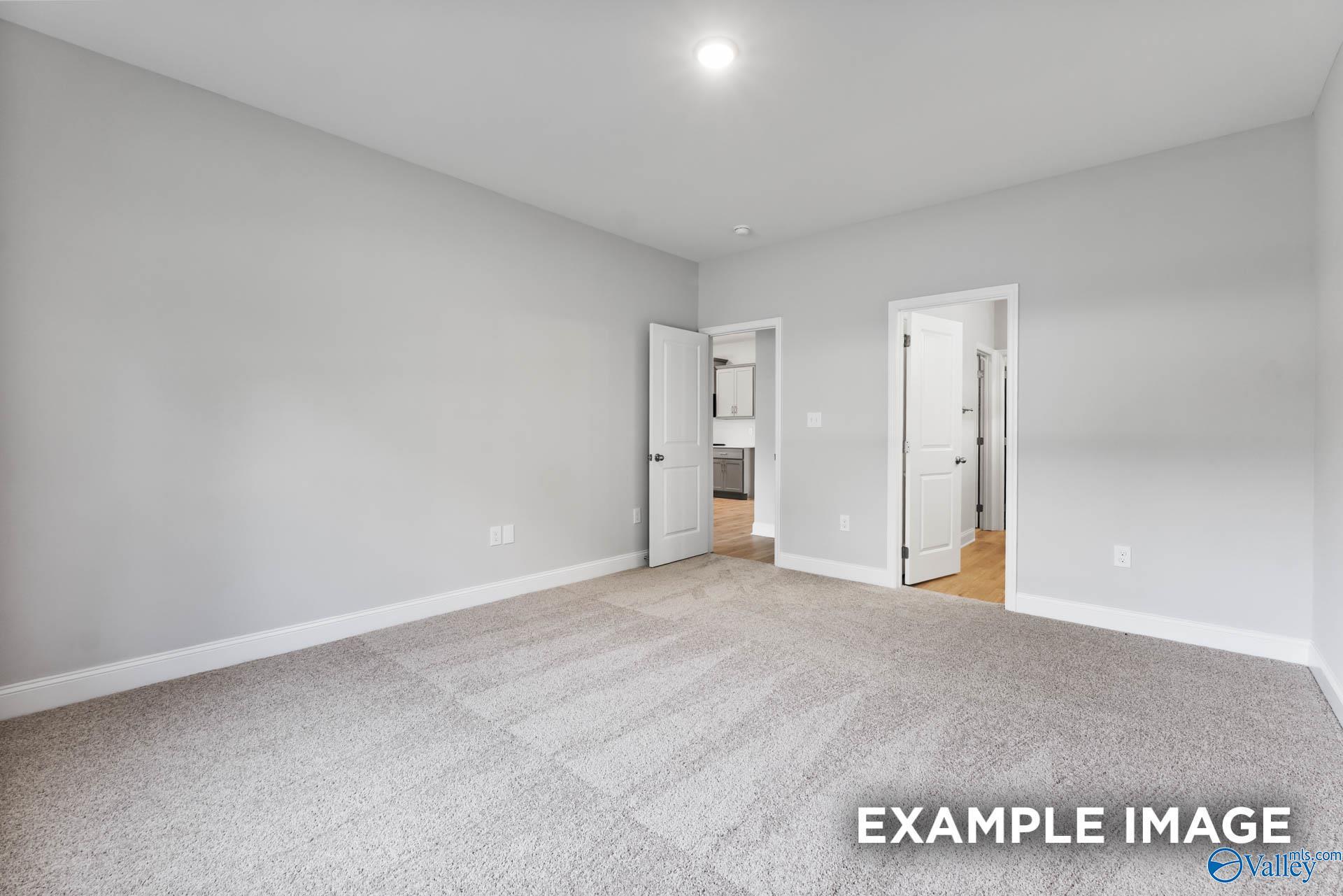 Spacious secondary bedroom with gray walls, carpeted floor, and adjacent bathroom door in 4-bedroom Davidson Homes The Daphne F, Hazel Green, Alabama
