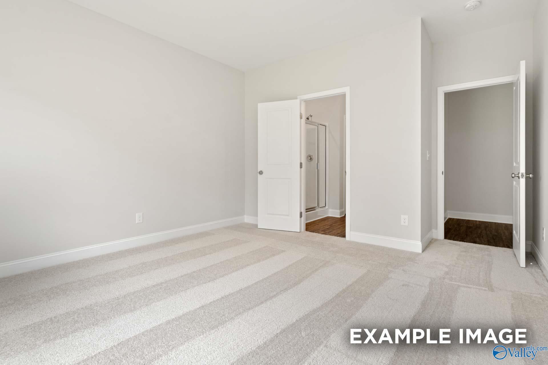 Bright carpeted bedroom with walk-in shower access and hardwood flooring in Davidson Homes Asheville C plan, Huntsville, AL