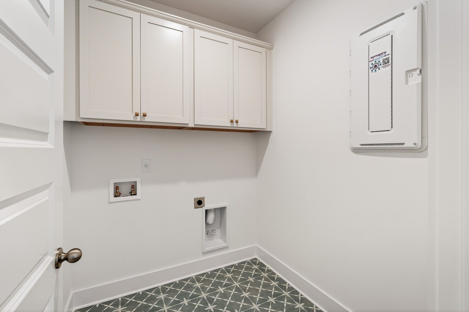 Modern laundry room featuring white shaker cabinets, washer-dryer hookups, and geometric tile floor in Davidson Homes Ridgeport C, Gallatin TN