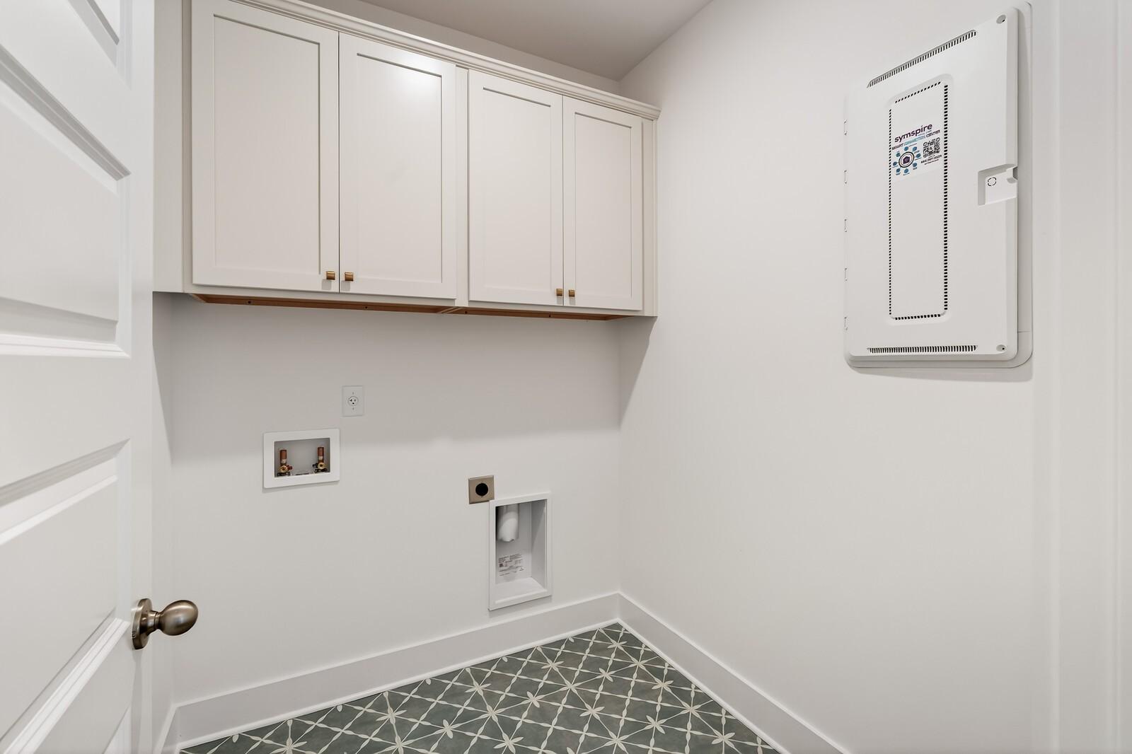 Modern laundry room featuring white shaker cabinets, washer-dryer hookups, and geometric tile floor in Davidson Homes Ridgeport C, Gallatin TN