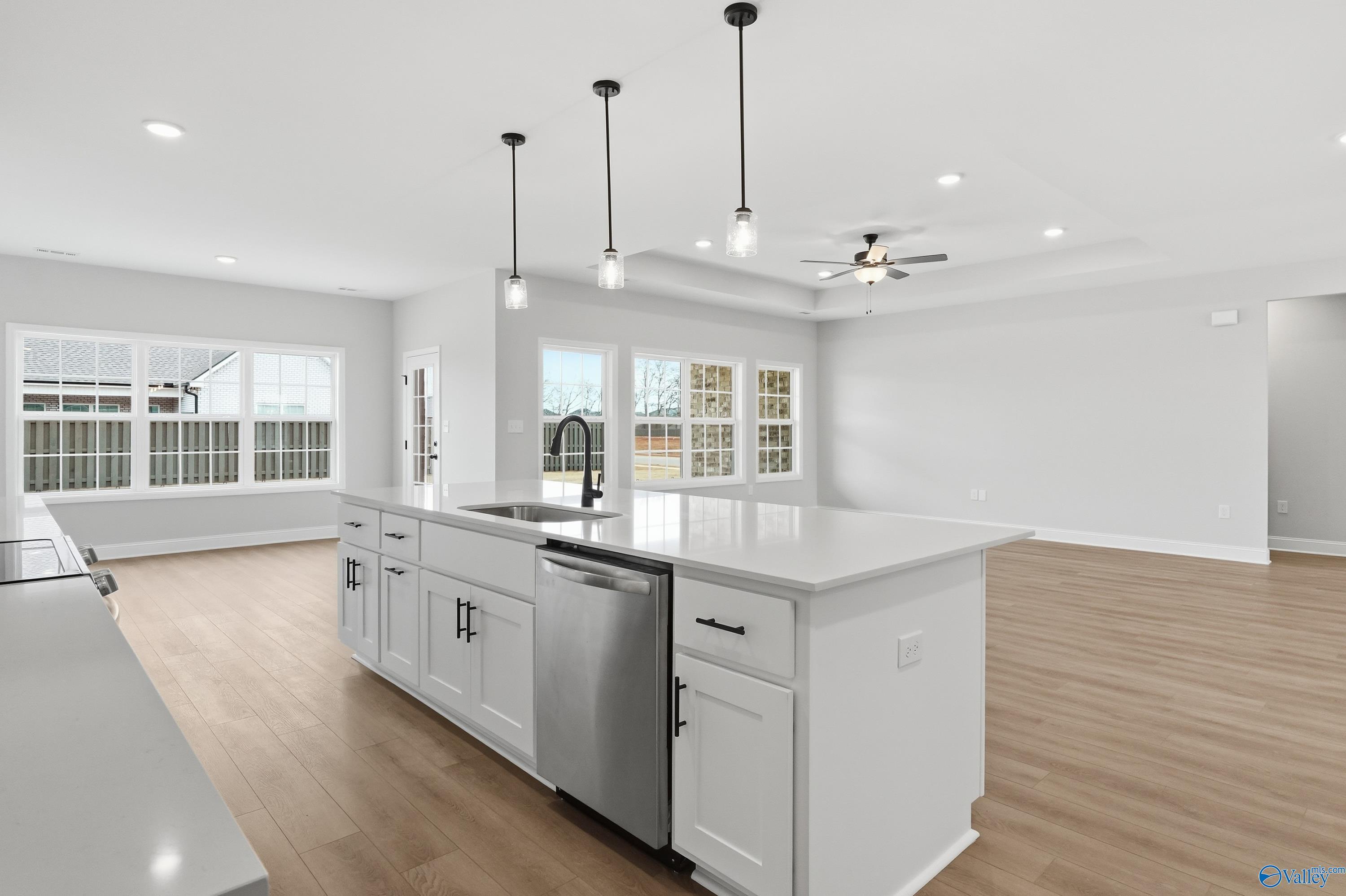 Modern open-concept kitchen with white island, stainless dishwasher, pendant lights, and large windows in The Finleigh by Davidson Homes, Meridianville, AL