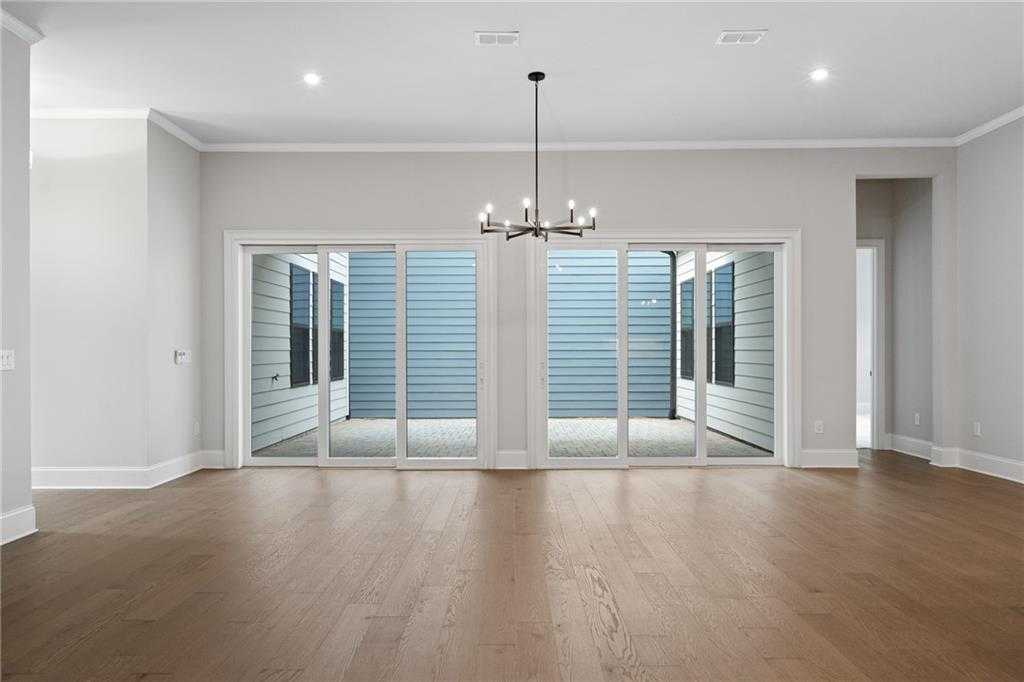 Spacious living room with oak hardwood floors, modern chandelier, and large glass doors to blue patio in Davidson Homes The Seaside B, Woodstock, GA