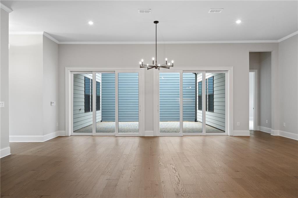 Spacious living room with oak hardwood floors, modern chandelier, and large glass doors to blue patio in Davidson Homes The Seaside B, Woodstock, GA