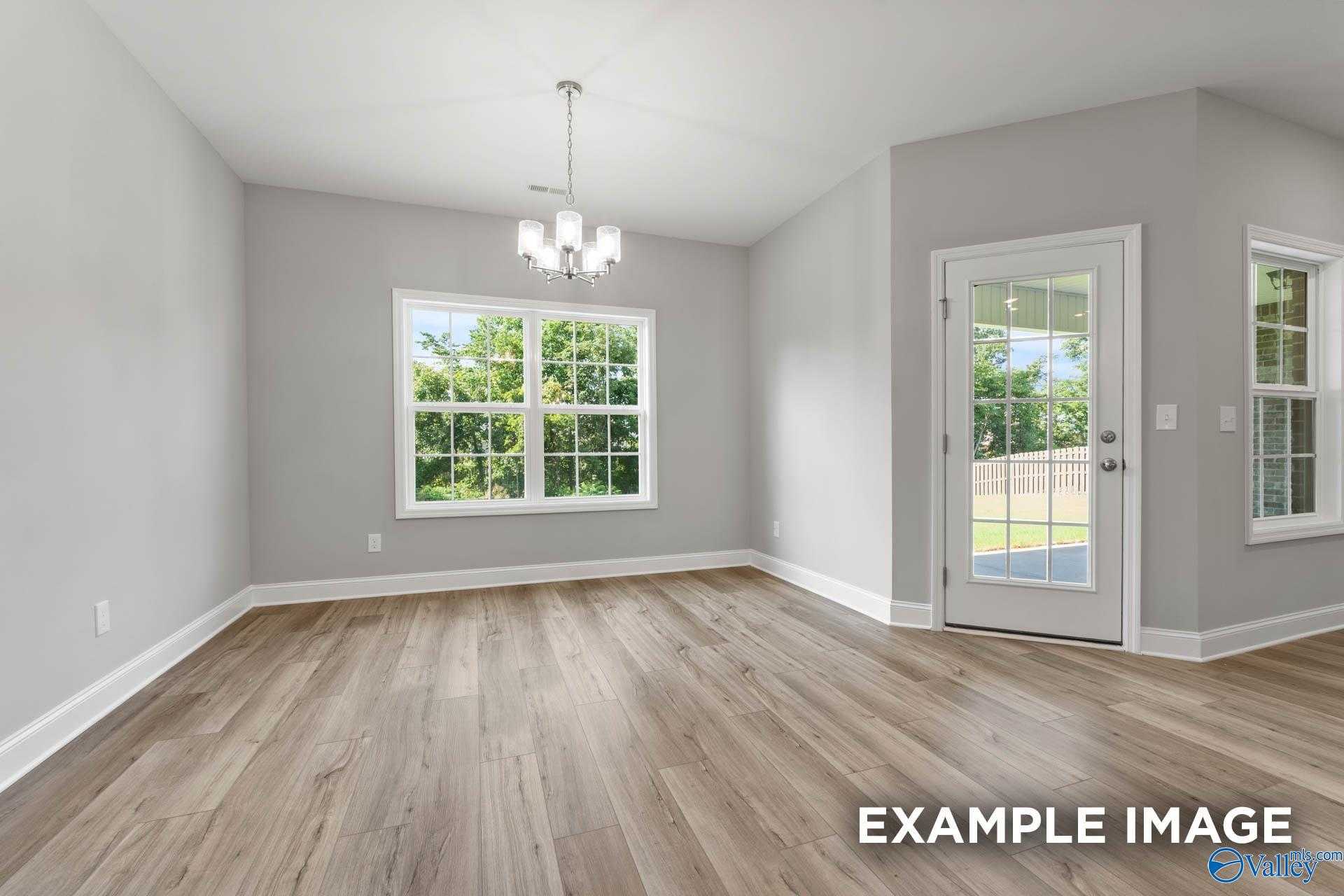 Bright dining room with hardwood floors, gray walls, chandelier, and French door to backyard in Davidson Homes The Rockford D, Hazel Green, Alabama