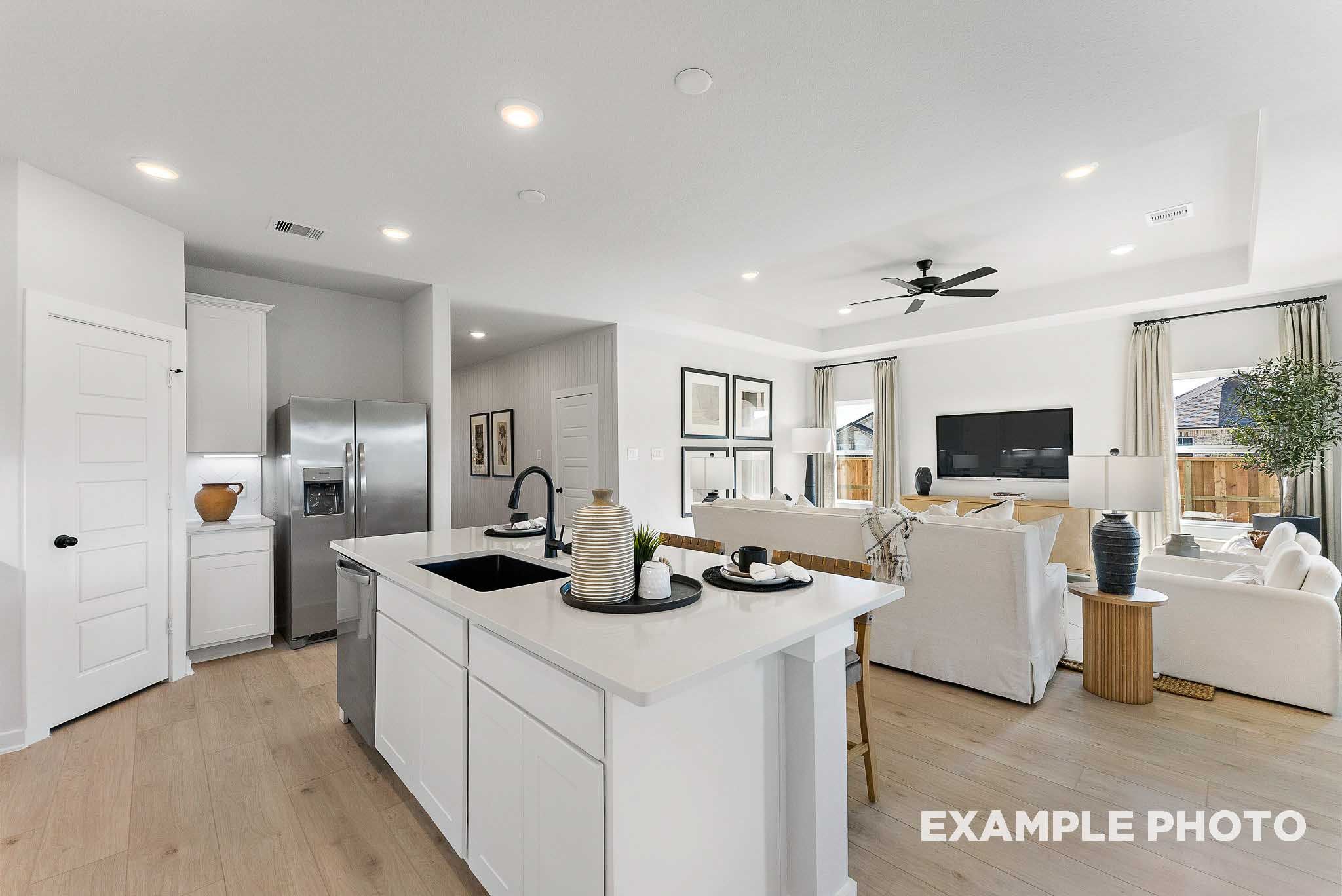 Open-concept kitchen and living room with white cabinets and kitchen island in The Everett E plan at Sundance Cove, Crosby.