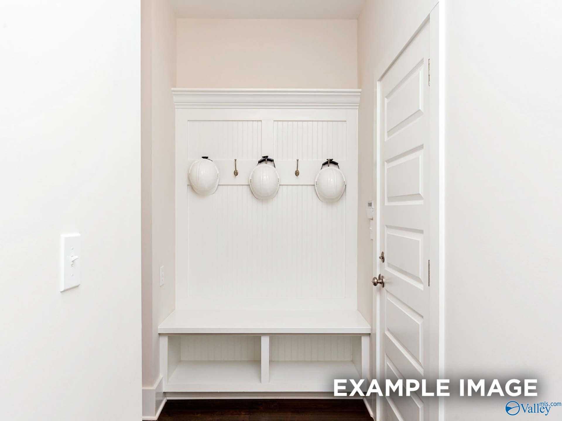 White beadboard mudroom with built-in lockers, bench, and hooks in Davidson Homes The Finleigh, Meridianville, Alabama