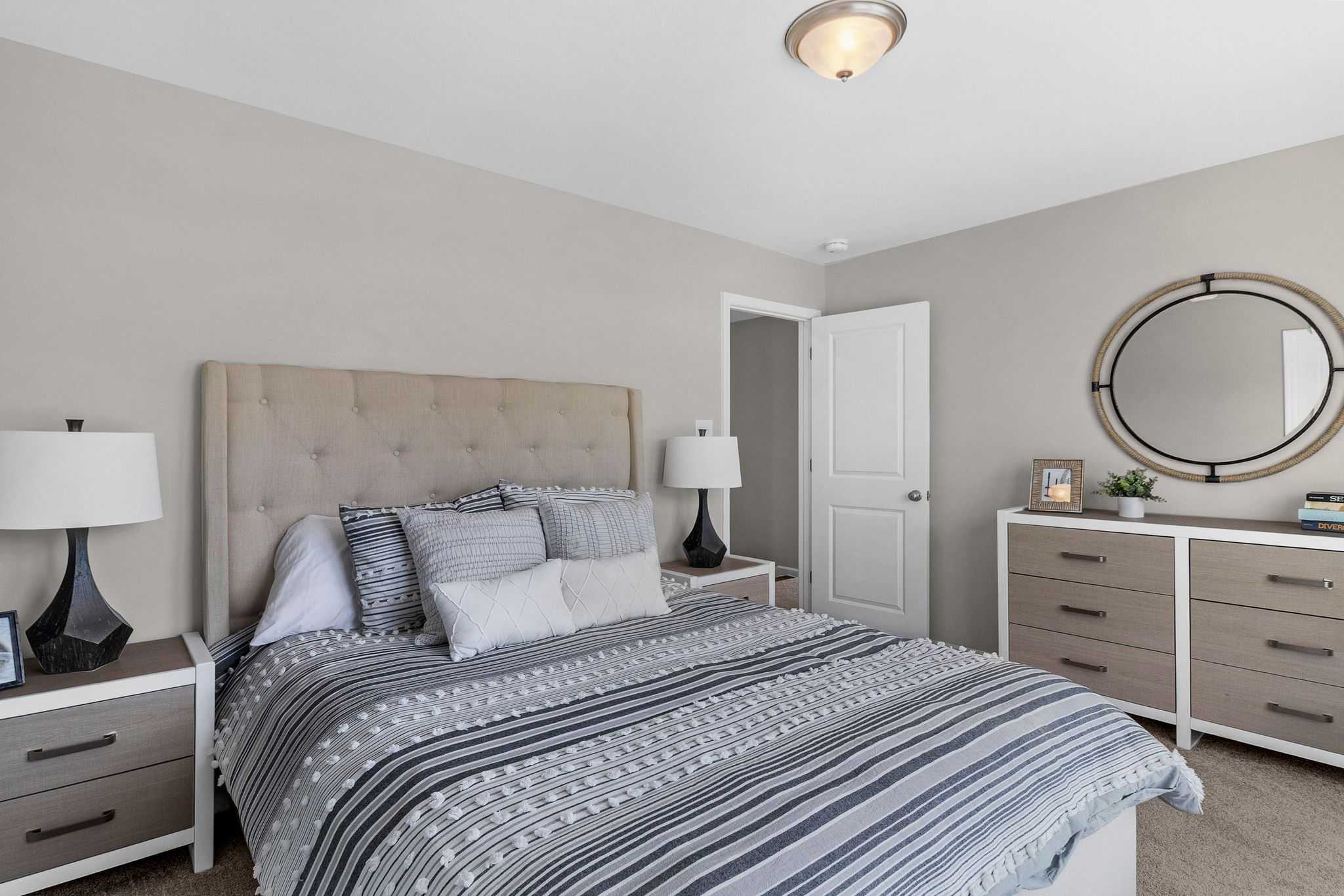 Modern bedroom interior at Ivy Glen Perry GA featuring upholstered headboard bed, striped duvet, and neutral tones