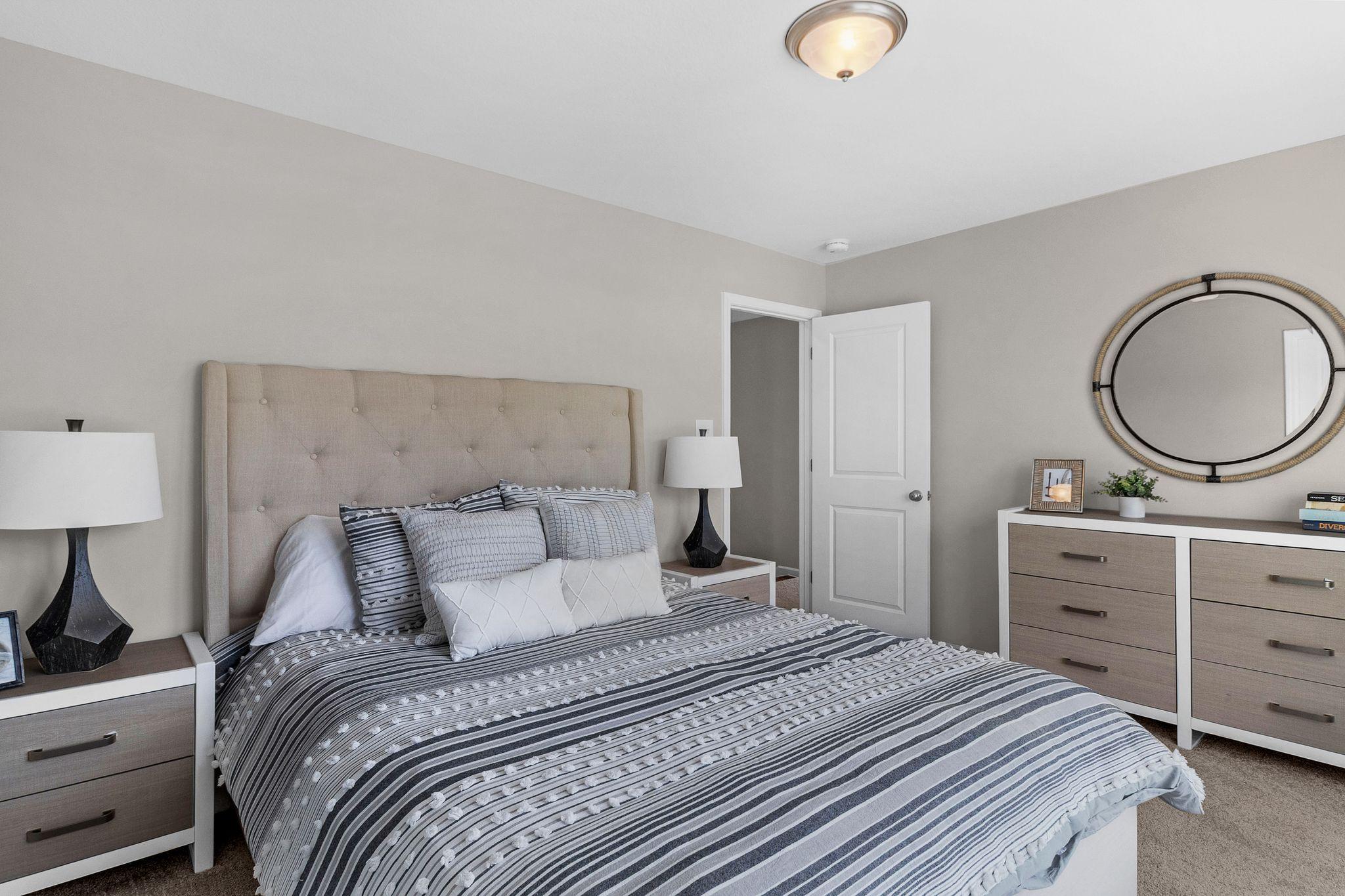 Modern bedroom interior at Ivy Glen Perry GA featuring upholstered headboard bed, striped duvet, and neutral tones