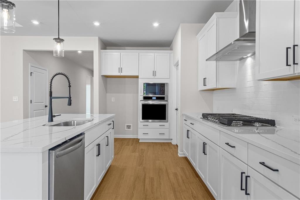 Modern white kitchen with quartz island, stainless appliances, double ovens in Davidson Homes Edison B, Loganville, GA