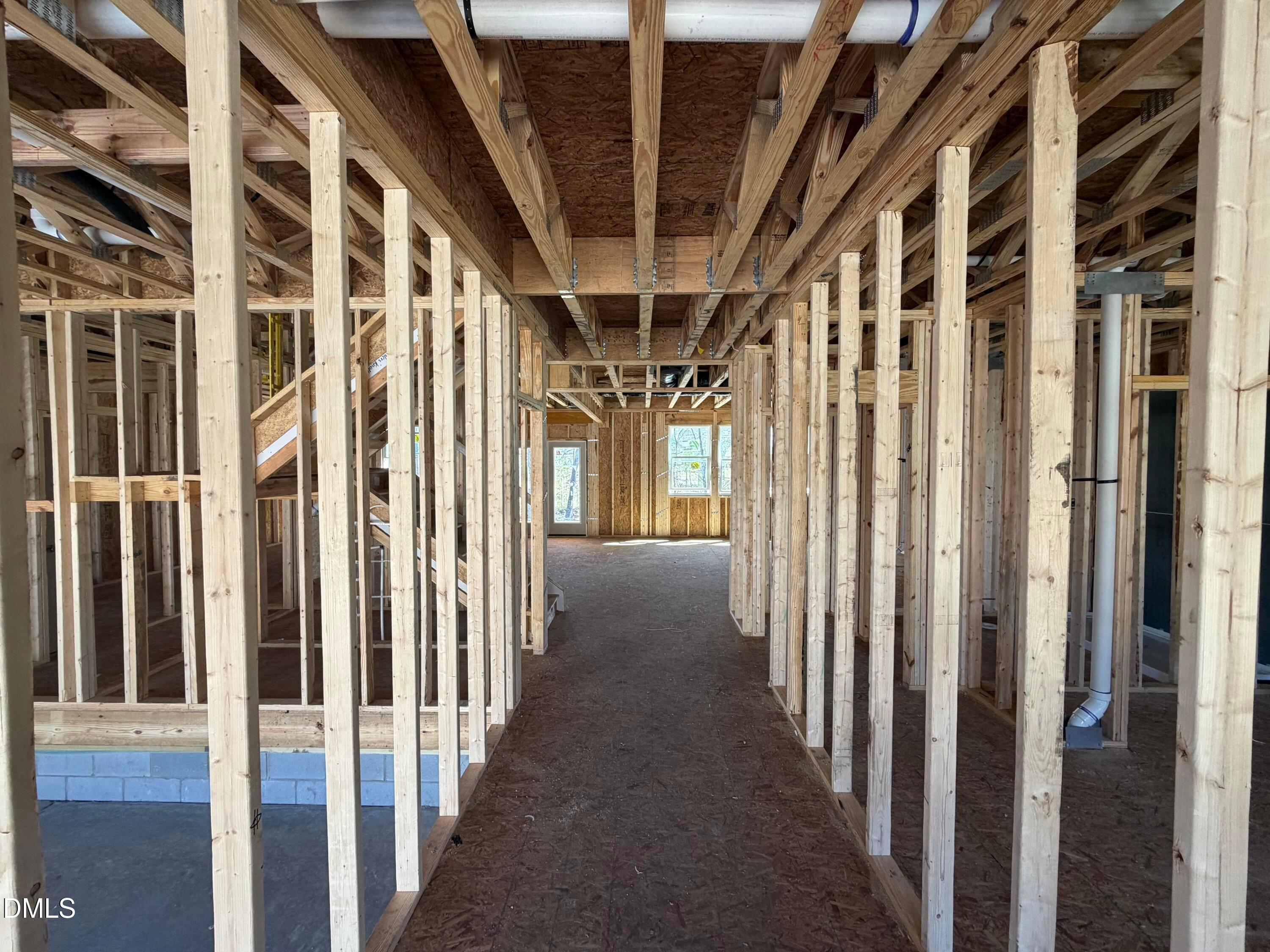 Exposed wooden framing of long hallway with plumbing pipes in The Hickory II B by Davidson Homes, Lillington NC