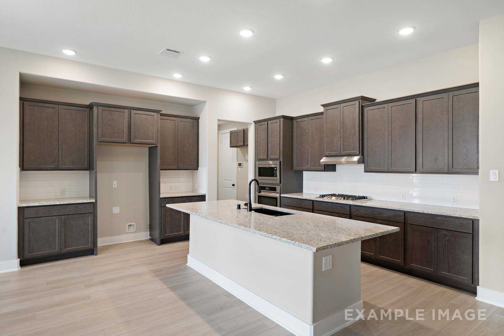 Modern kitchen in The Elizabeth A by Davidson Homes featuring dark wood cabinets, granite island, and stainless appliances