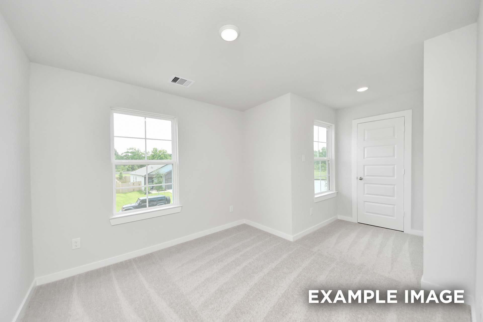 Bright empty bedroom with carpet, white walls, and windows overlooking backyard in Davidson Homes The Blanco E, Magnolia TX