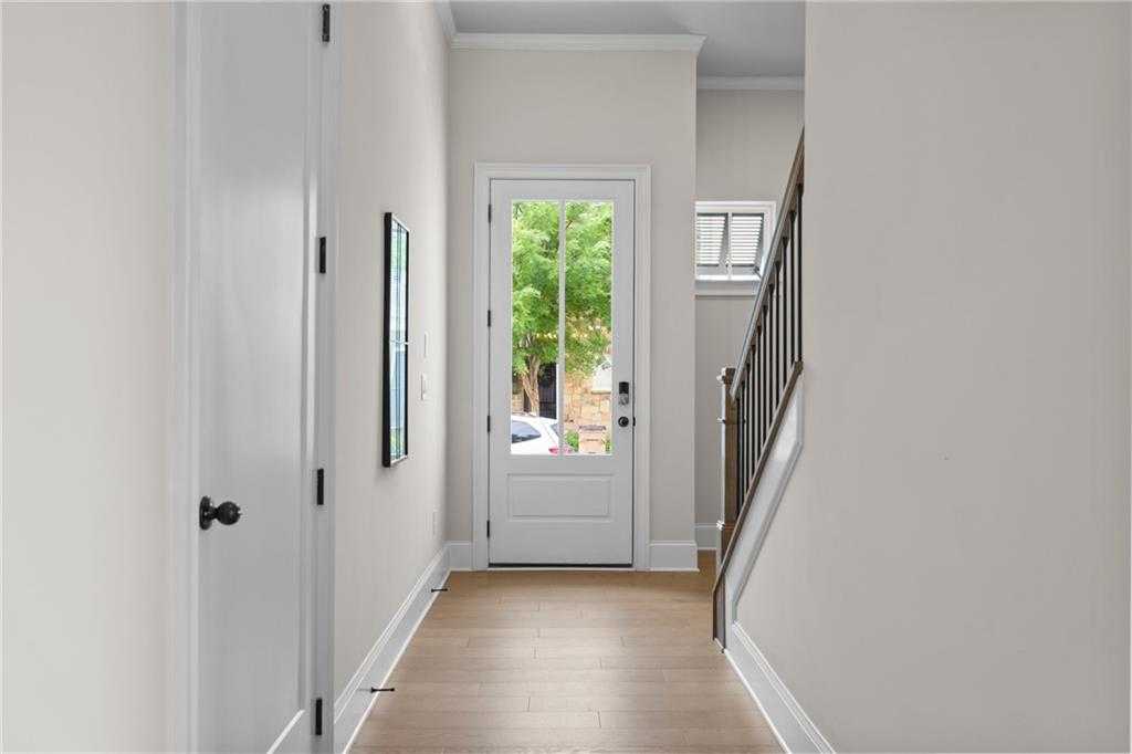 Bright entry foyer with oak hardwood floors, white paneled door, and wrought-iron staircase in Davidson Homes The Seaside B, Woodstock, GA