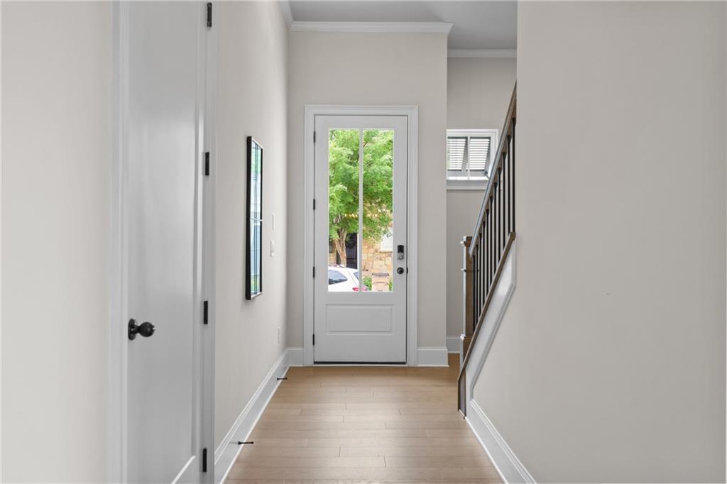 Bright entry foyer with oak hardwood floors, white paneled door, and wrought-iron staircase in Davidson Homes The Seaside B, Woodstock, GA