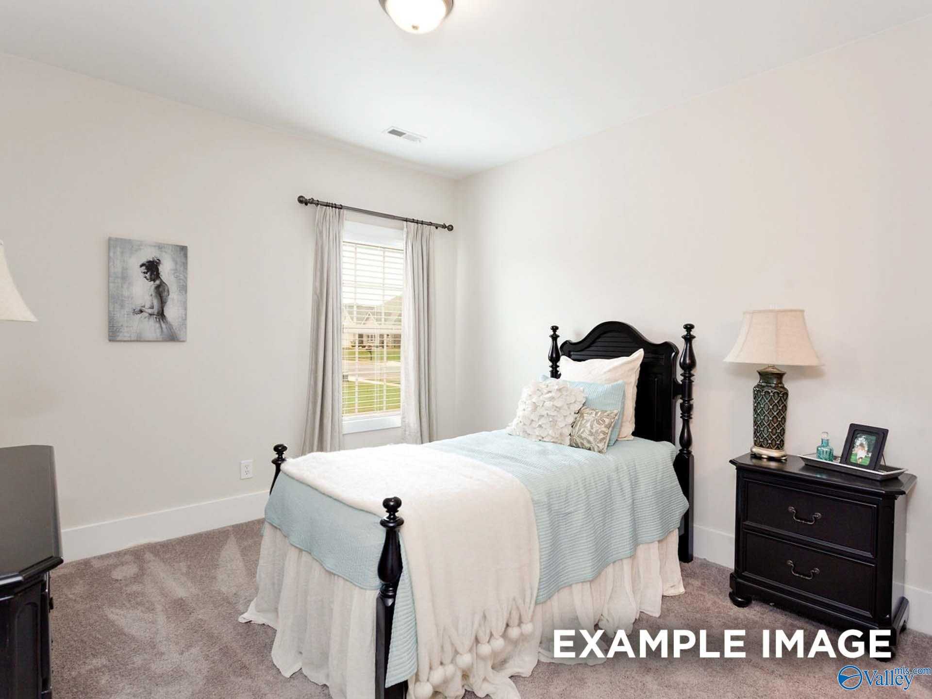 Cozy secondary bedroom featuring twin bed with blue bedding, black wooden furniture, and window view in Davidson Homes The Finleigh, Meridianville, Alabama