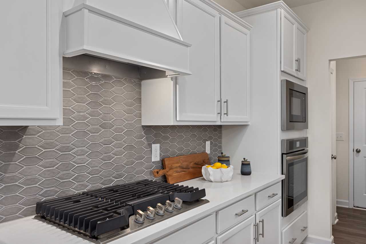 Spacious kitchen in Gregory Village Townhomes, Lillington NC with white shaker cabinets, gray herringbone backsplash, gas range