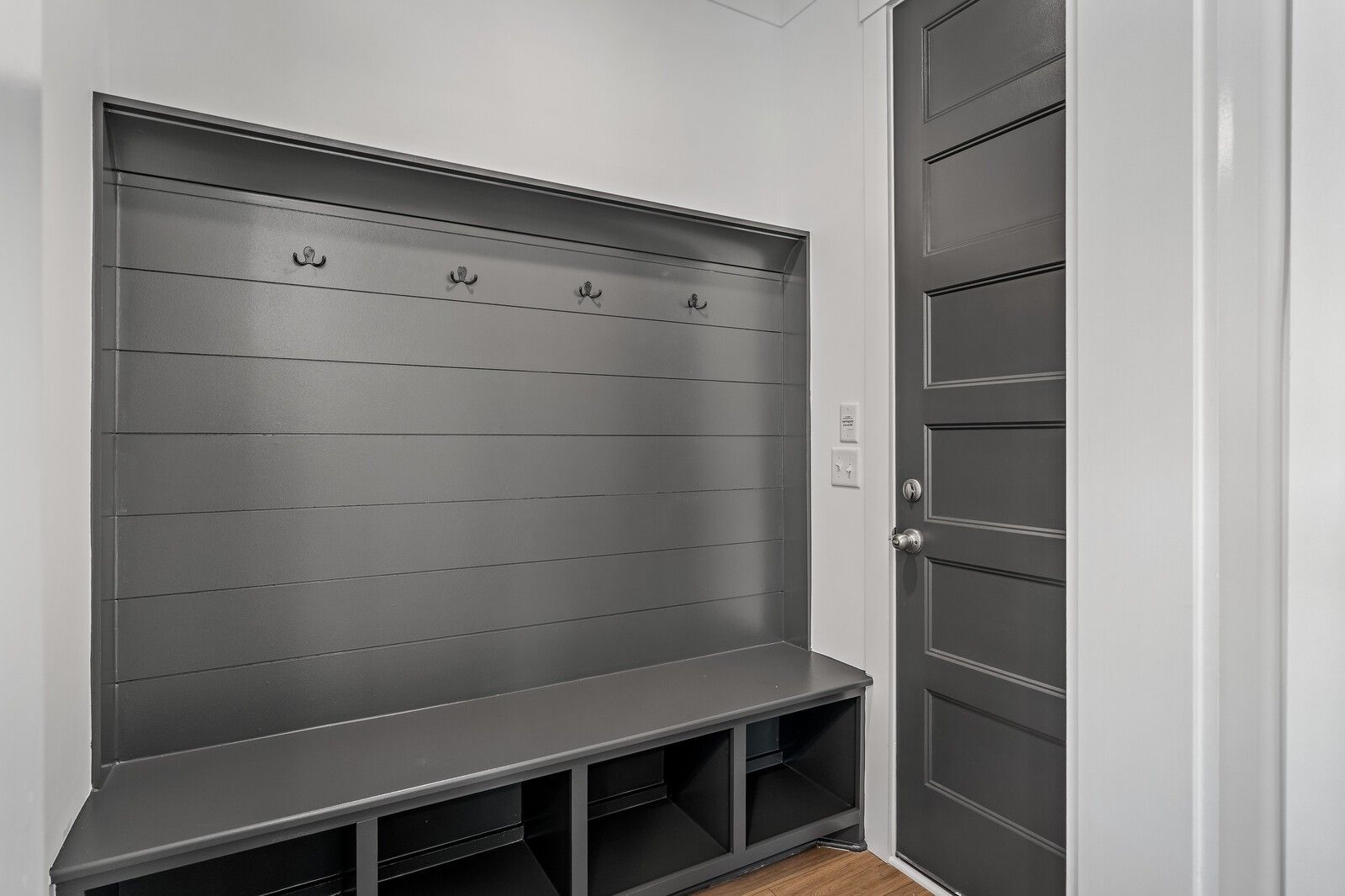 Gray shiplap mudroom with coat hooks, built-in bench, and storage cubbies in Davidson Homes The Hawkins, Murfreesboro, Tennessee
