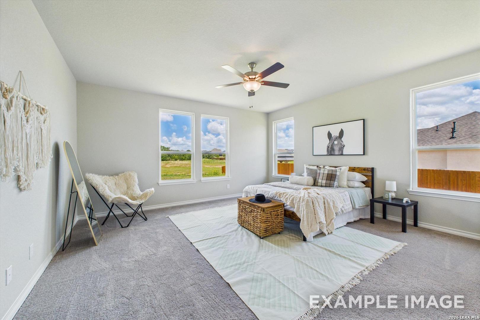 Bright, spacious bedroom in The Foster F floor plan at Potranco Oaks, featuring modern decor and large windows.