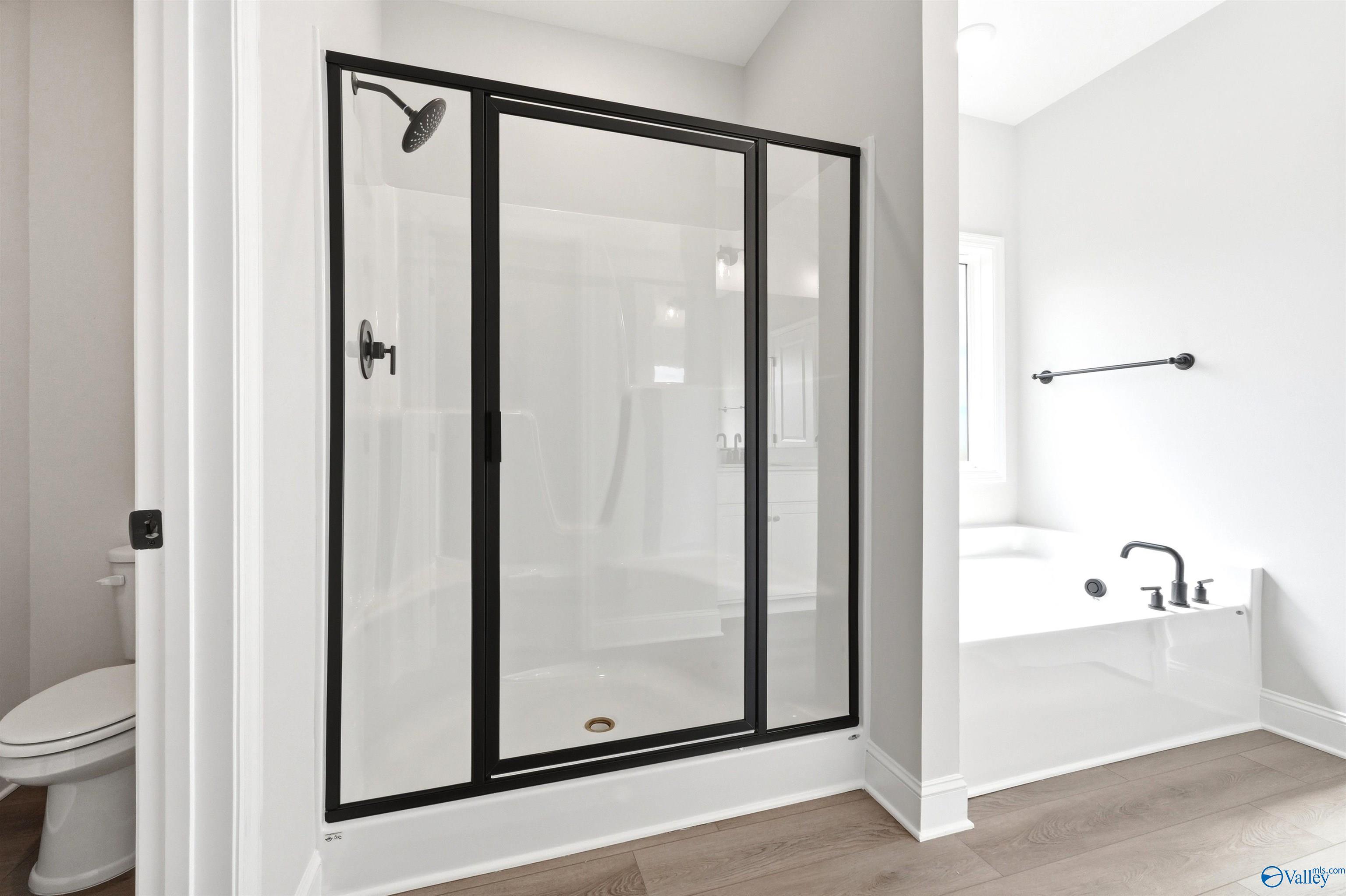 Modern primary bathroom with walk-in shower and soaking tub in The Daphne F plan at Berry Cove, New Market, Alabama.