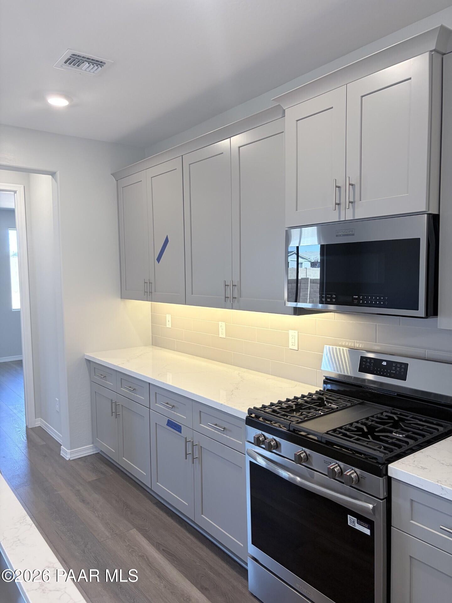 Modern kitchen with gray cabinets, quartz countertops, and stainless steel appliances in The Frontier A, Pronghorn Ranch.