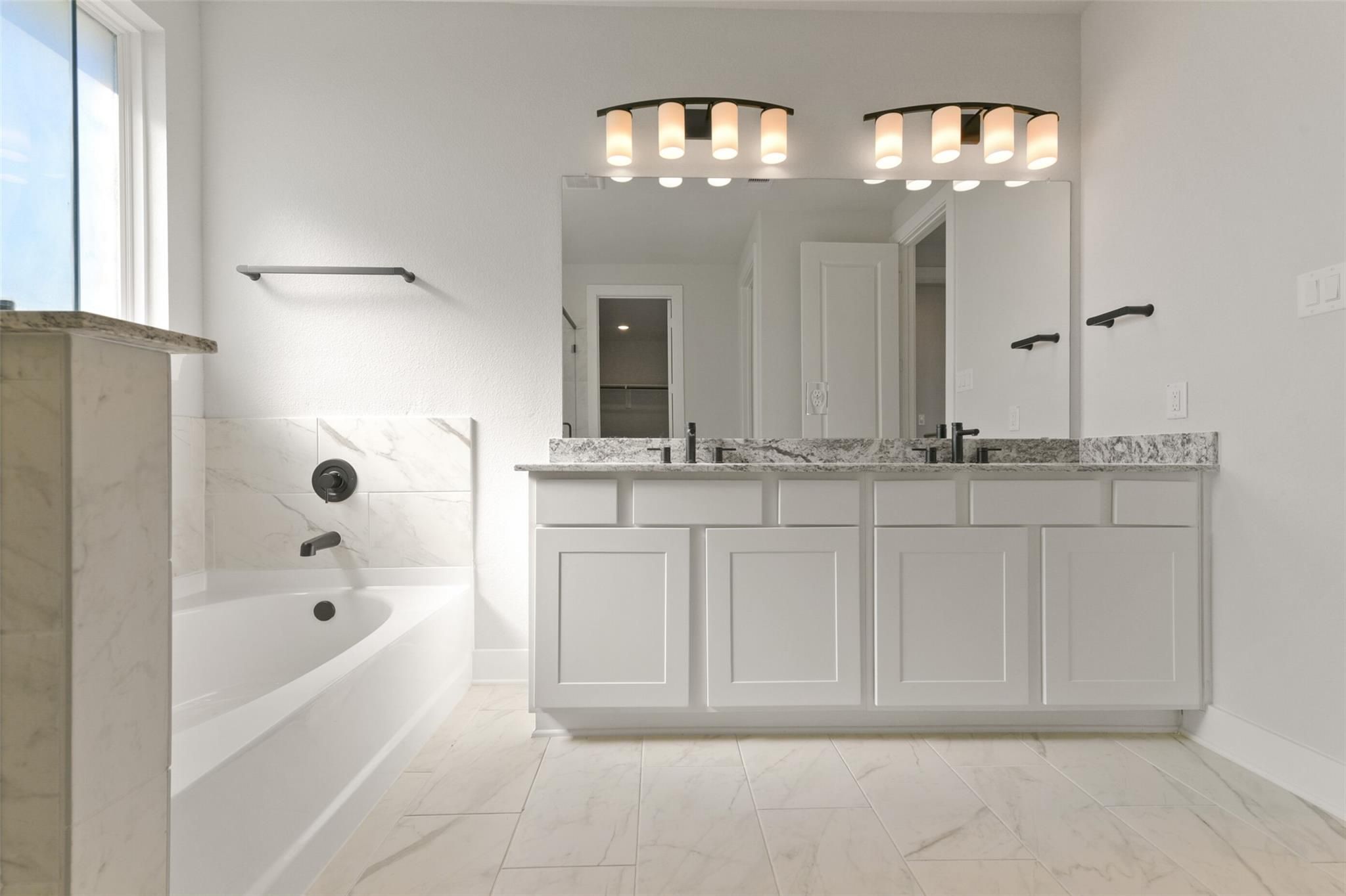 Elegant master bathroom with double marble vanity, freestanding tub, and white cabinetry in Davidson Homes The Edward C, Lago Mar, Texas City