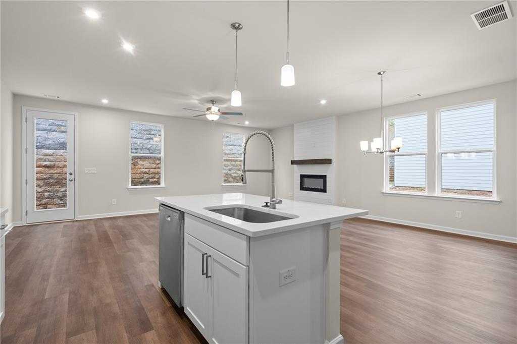 Open-concept kitchen with white island, farmhouse sink, hardwood floors, and gas fireplace in Davidson Homes The Marion B, Kennesaw, GA