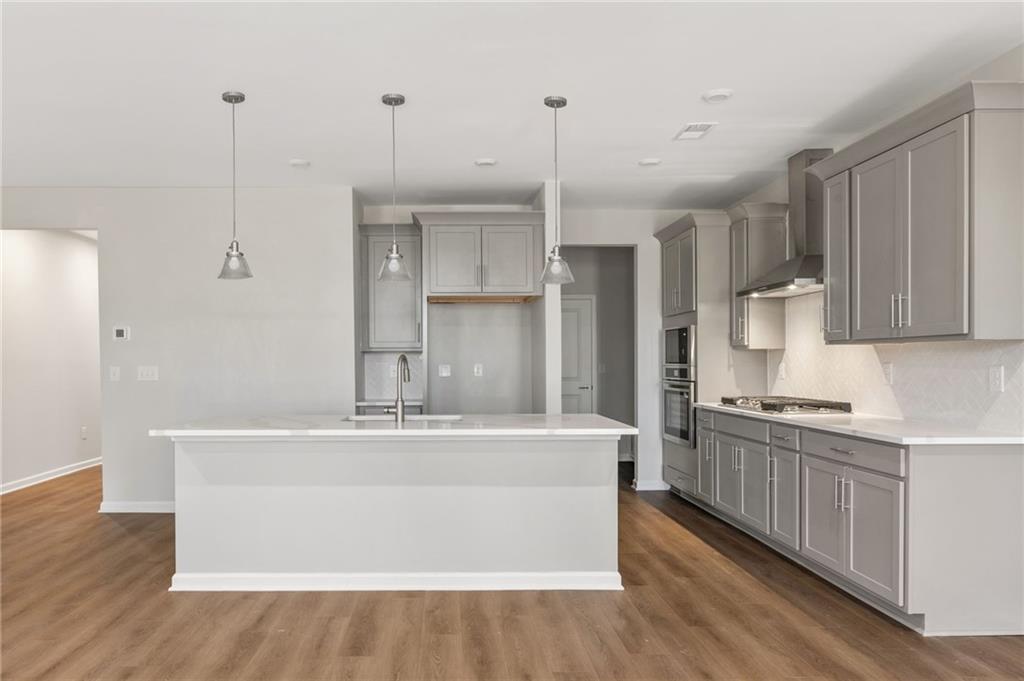 Modern kitchen with white quartz island, gray shaker cabinets, stainless steel appliances in Davidson Homes The Marion A, Winder, GA