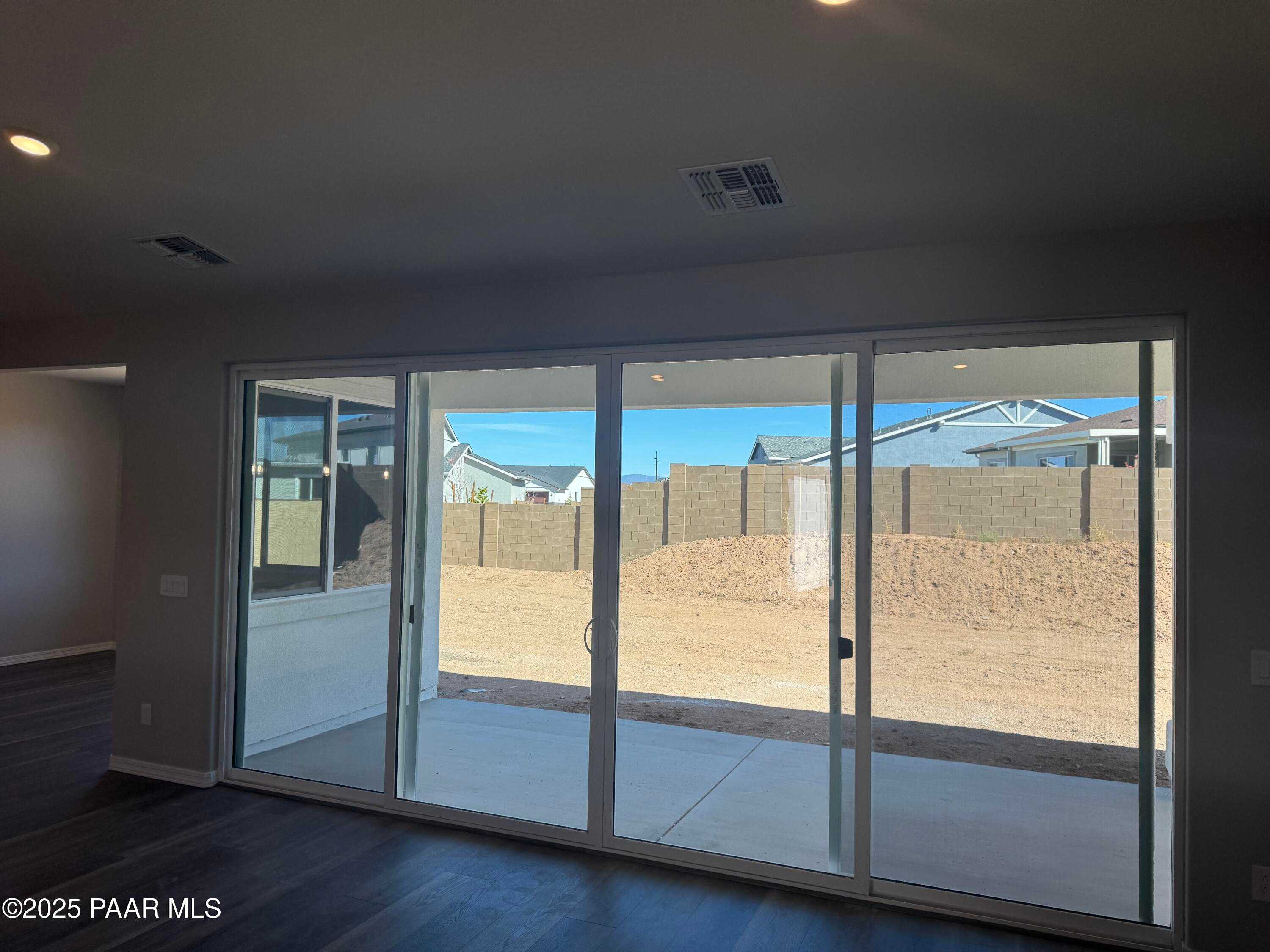 Large sliding glass doors opening to expansive dirt backyard with block fence in modern 3-bedroom Davidson Homes The Monarch E, Prescott AZ