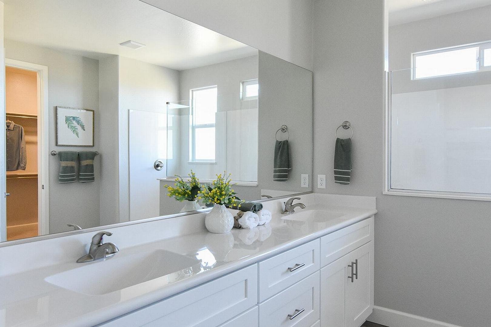 Spacious master bathroom in The Summit E with double white vanity, gray walls, and walk-in closet